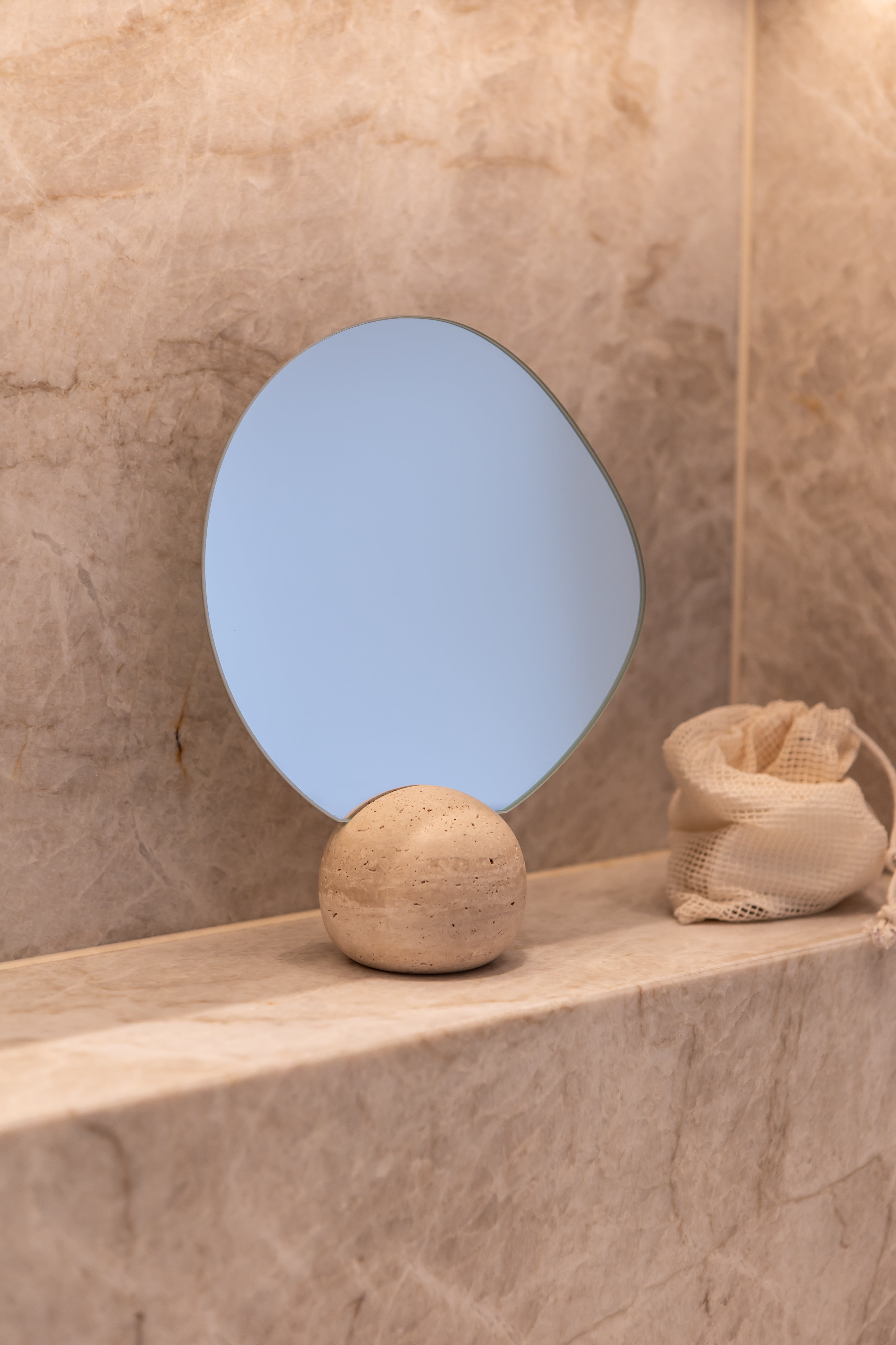 Asta bordspejlet med travertin fod stylet på et badeværelse.