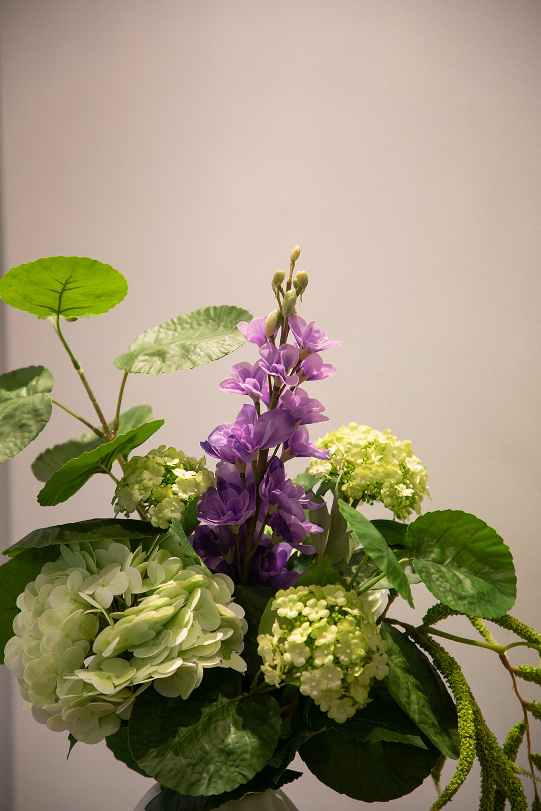 Nærbillede af basis buket af kunstige blomster i grønne nuancer, hvor der er tilføjet en lilla stilk.