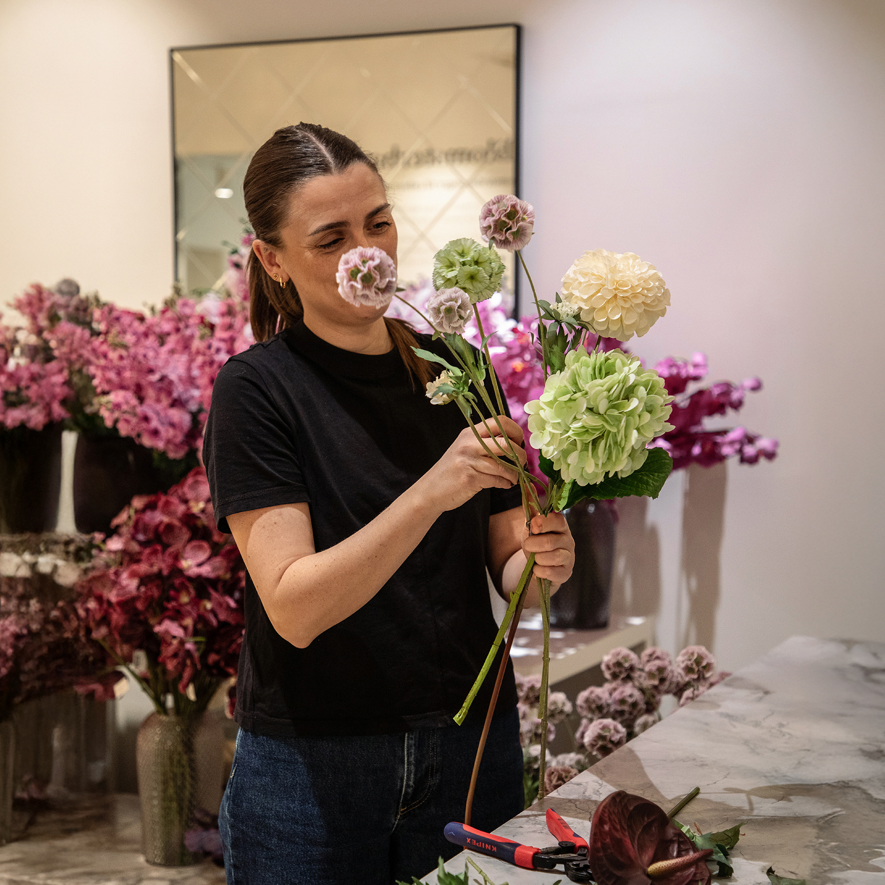 En buket af naturtro kunstige blomster bliver bundet.