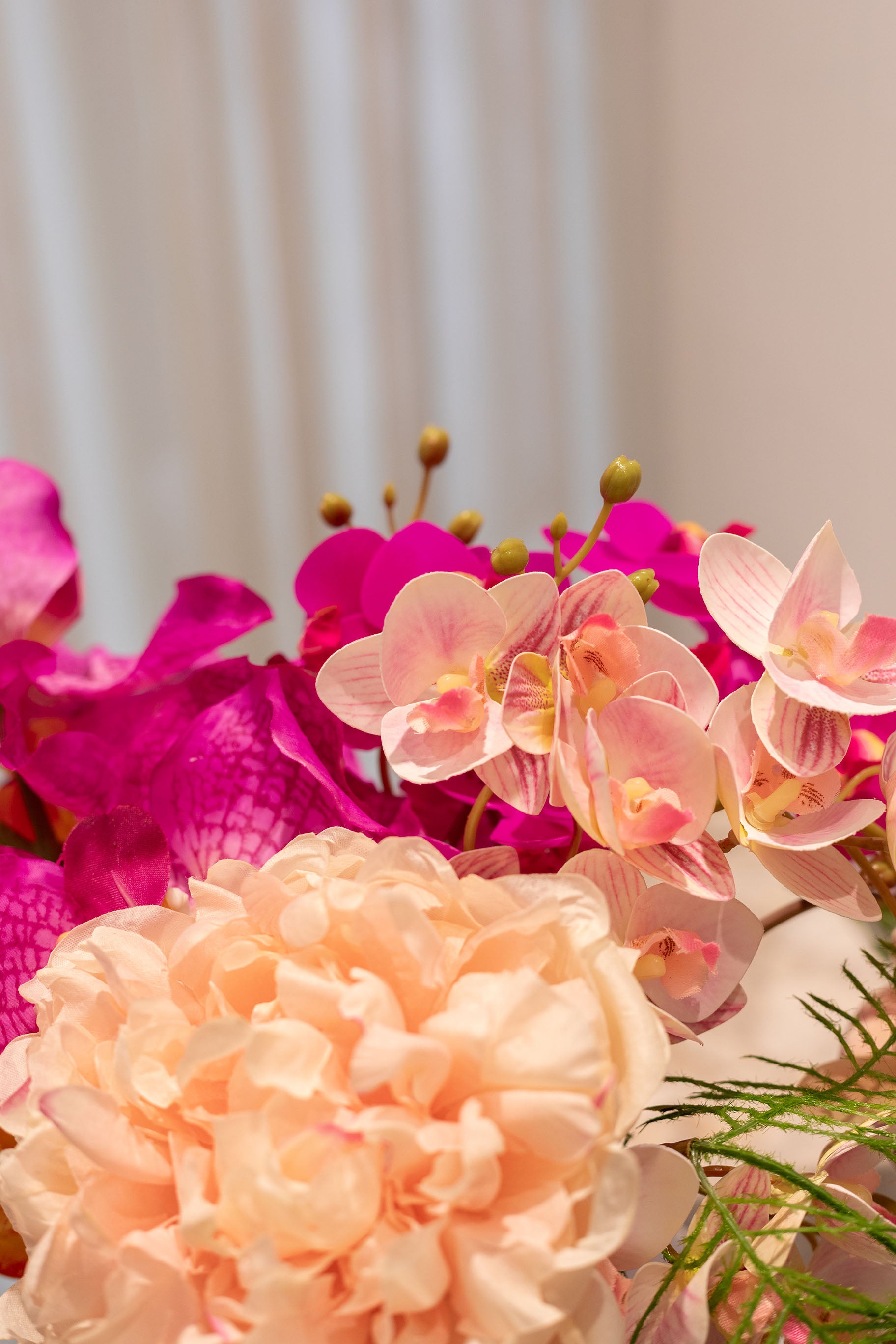 Nærbillede af buket af kunstige blomster i rose, lilla, grønne og orange nuancer.