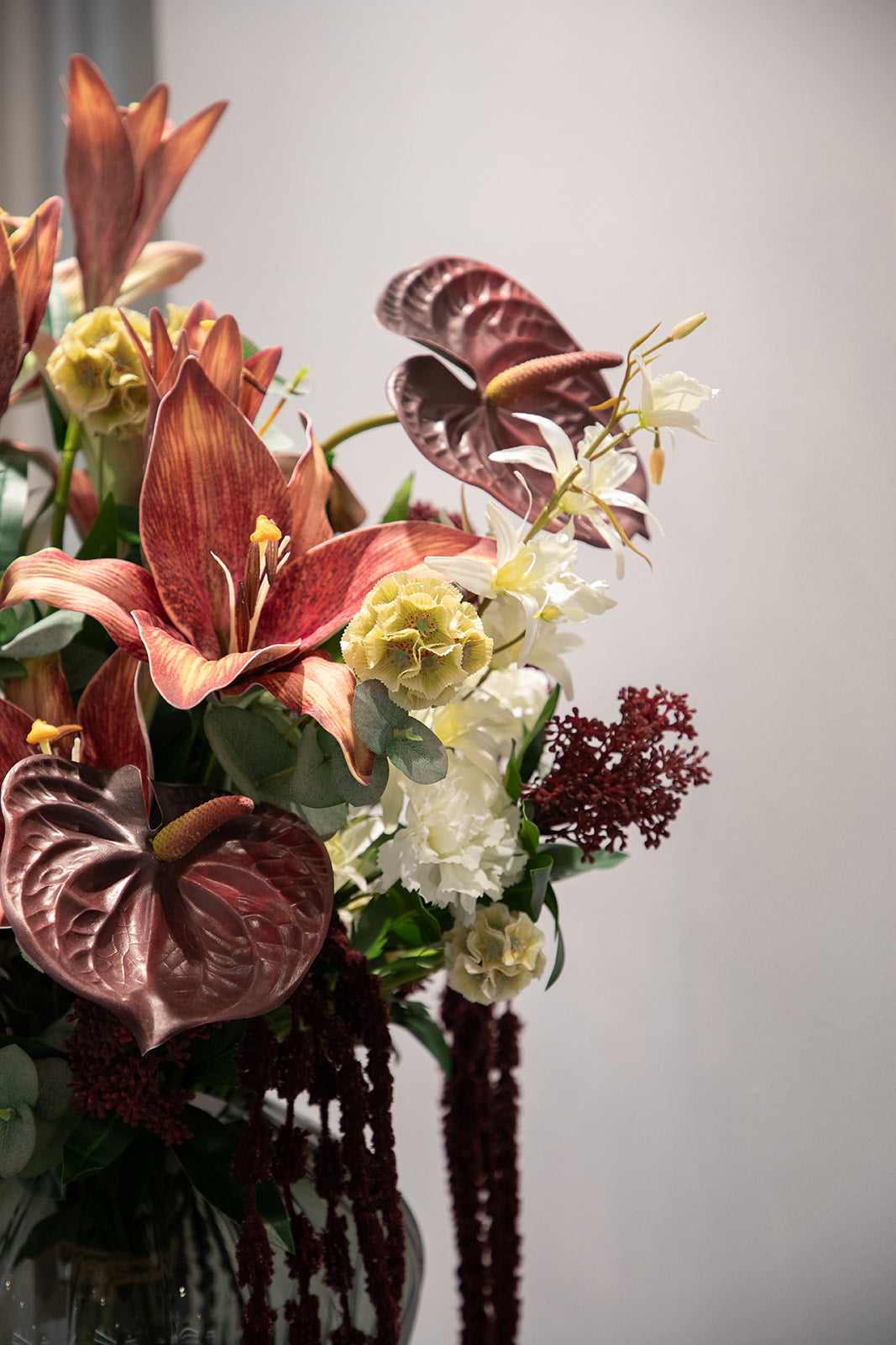 Nærbillede af en stor buket af kunstige blomster i røde, hvide og creme nuancer.