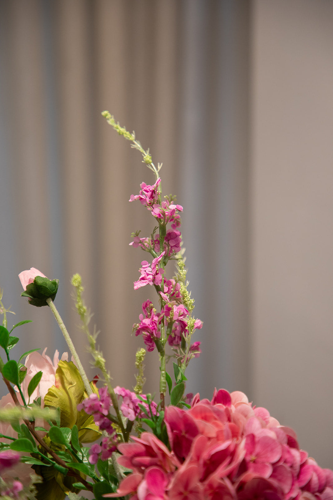 Nærbillede af en buket af kunstige blomster i lyserøde og grønne nuancer.