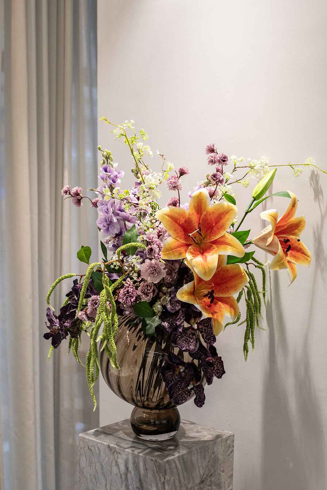 Kunstige blomster sammensat til en overdådig buket. Buketten er stylet i Meadow swirl vasen i farven topaz i large.