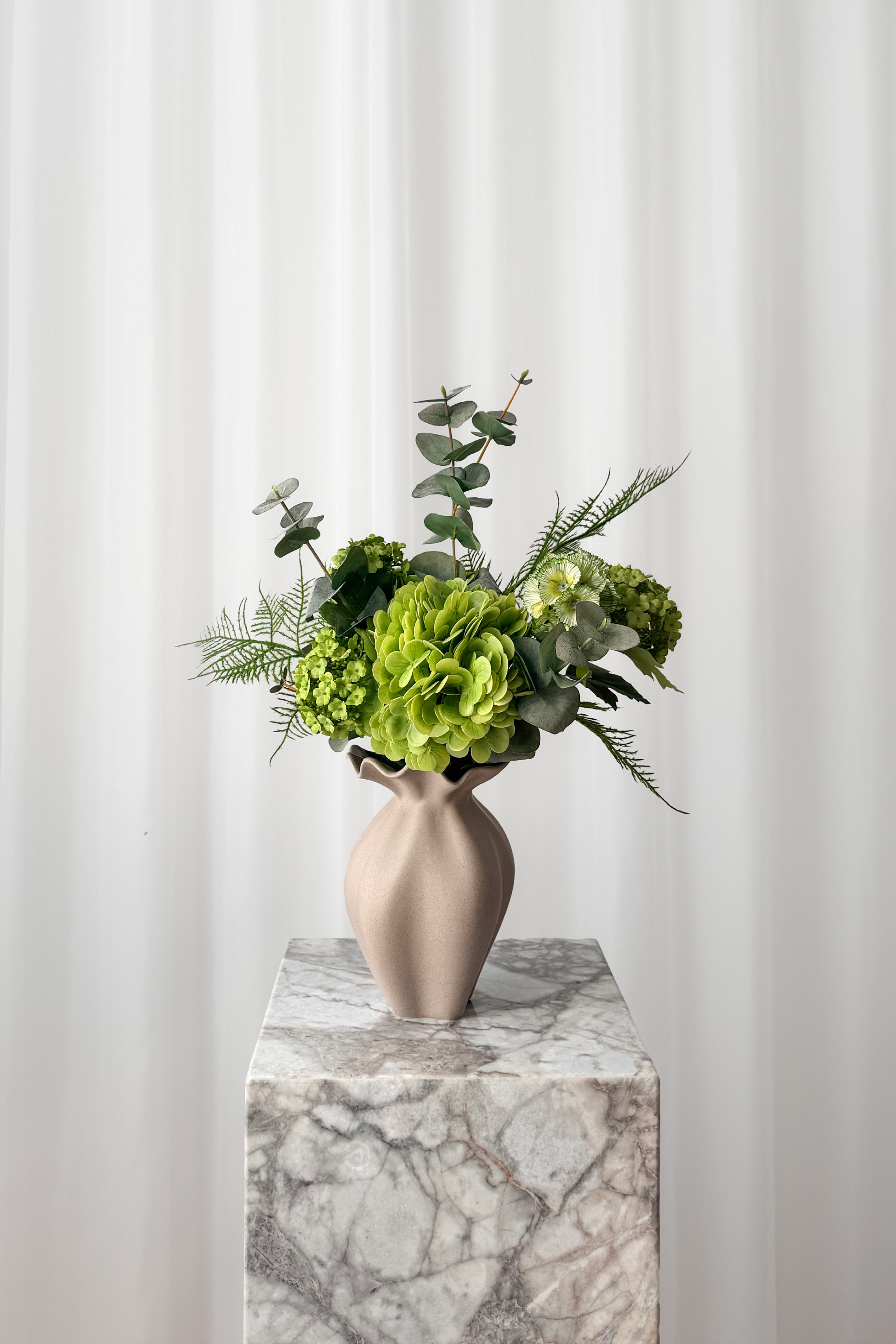 Kunstig buket af naturtro blomster i grønne forårsnuancer.