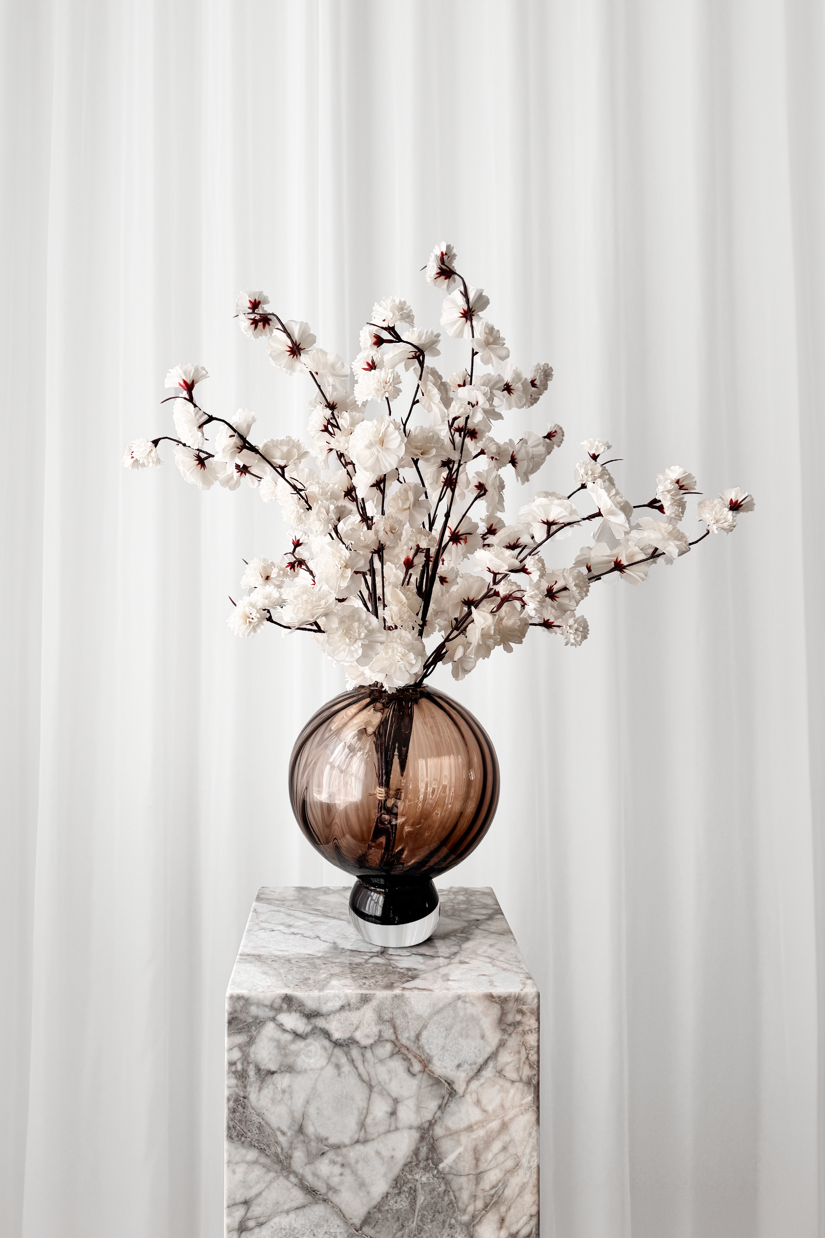 Hvide kirsebærblomstergrene stylet i den brune Meadow glasvase.