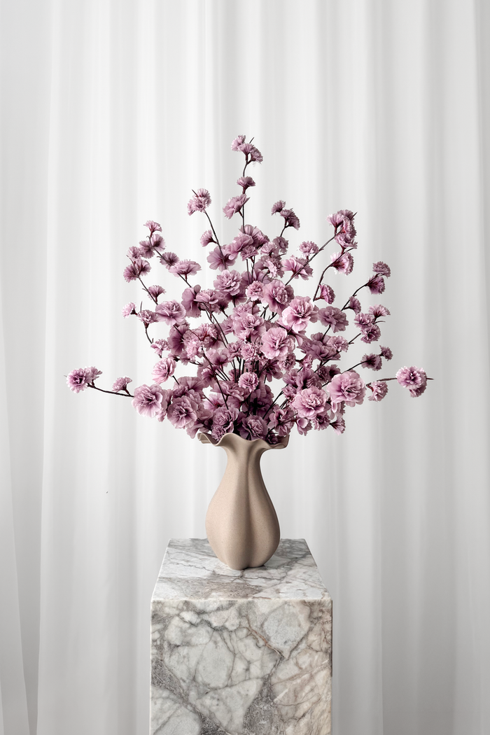 Buket af lilla kirsebærgrene stylet i en keramikvase. Blomsterne er naturtro kunstige blomster fra Specktrum.