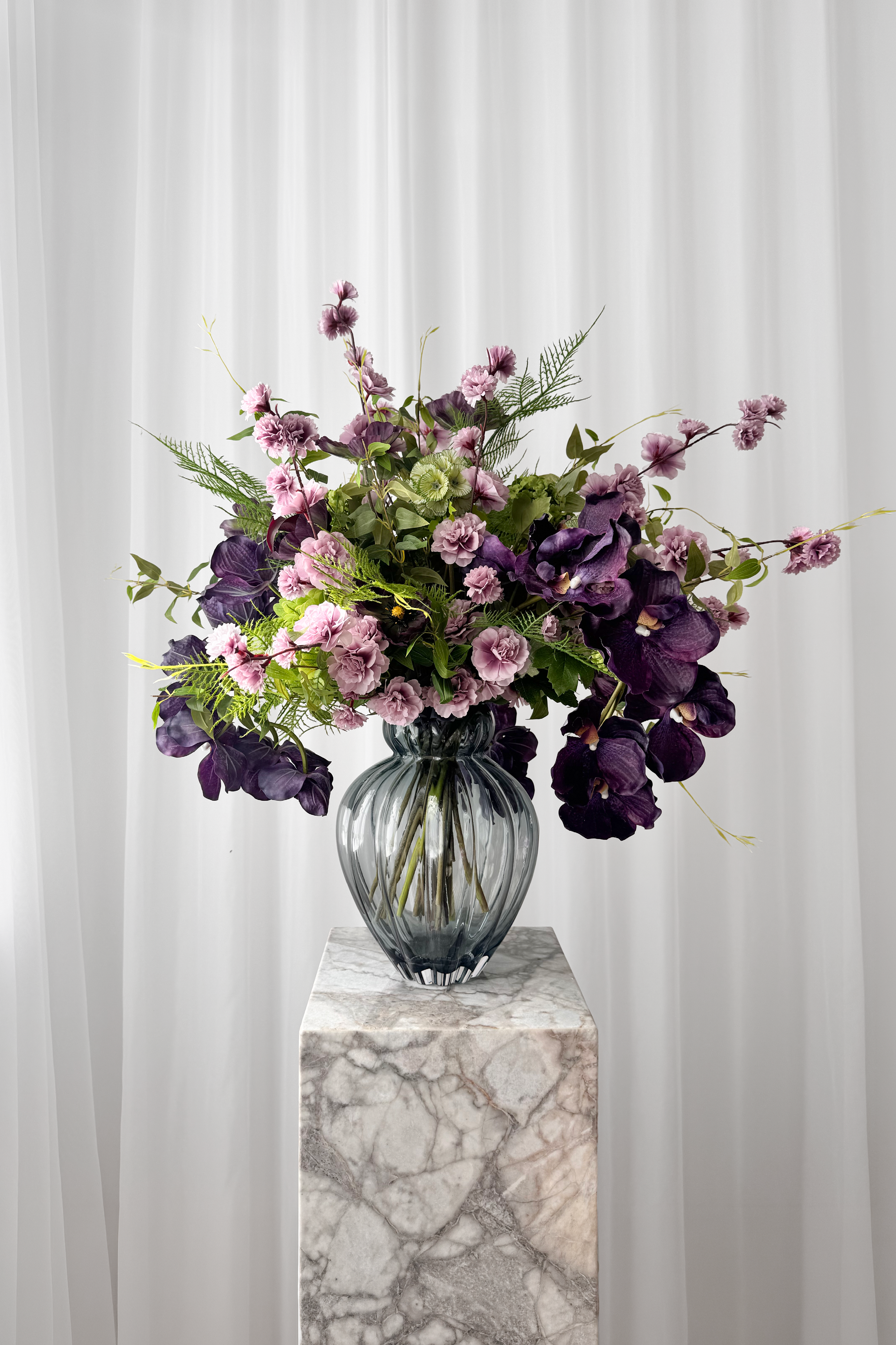 Overdådig buket i lilla nuancer stylet i en glasvase. Blomsterne er naturtro kunstige blomster fra Specktrum.