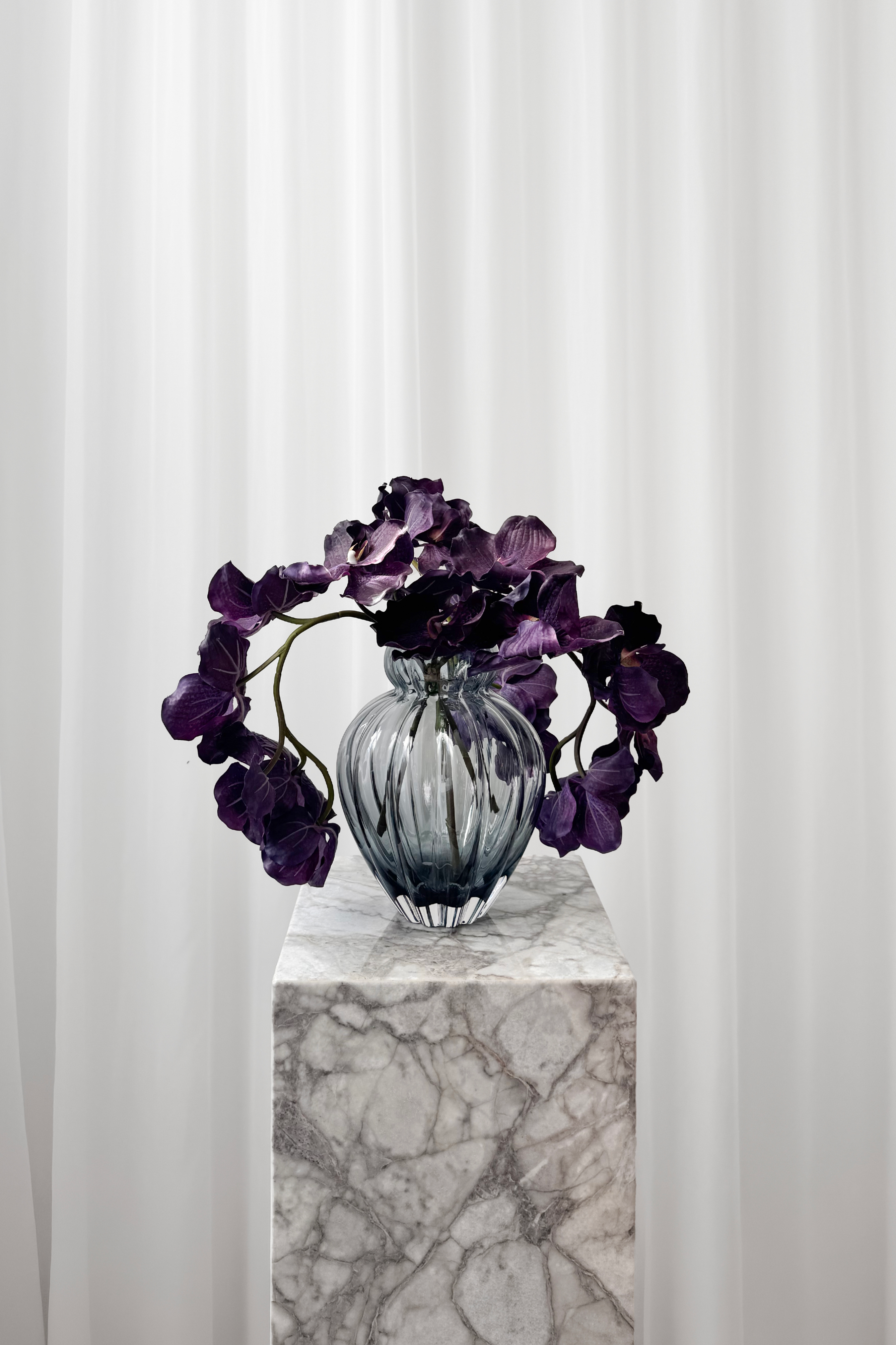 Buket af lilla orkideer stylet i en lilla glasvase fra Specktrum.