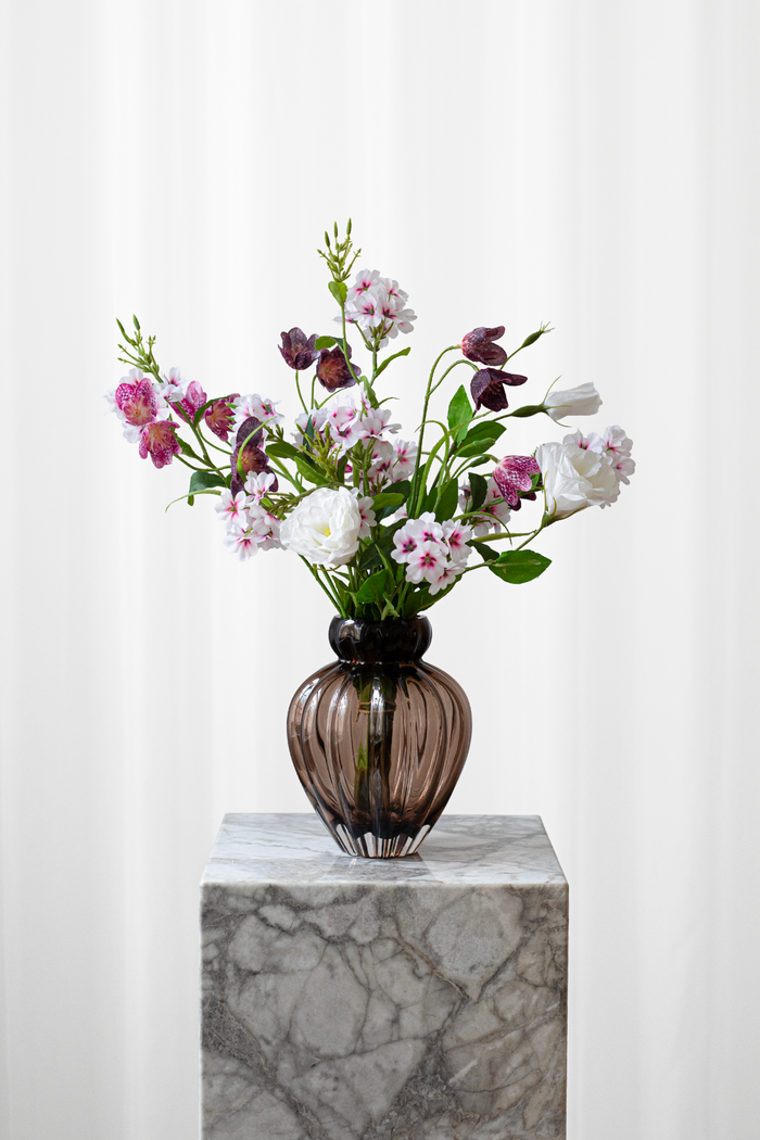 Buket af kunstige blomster, der ser ægte ud. Buketten er i hvide, lilla og lyserøde farver.