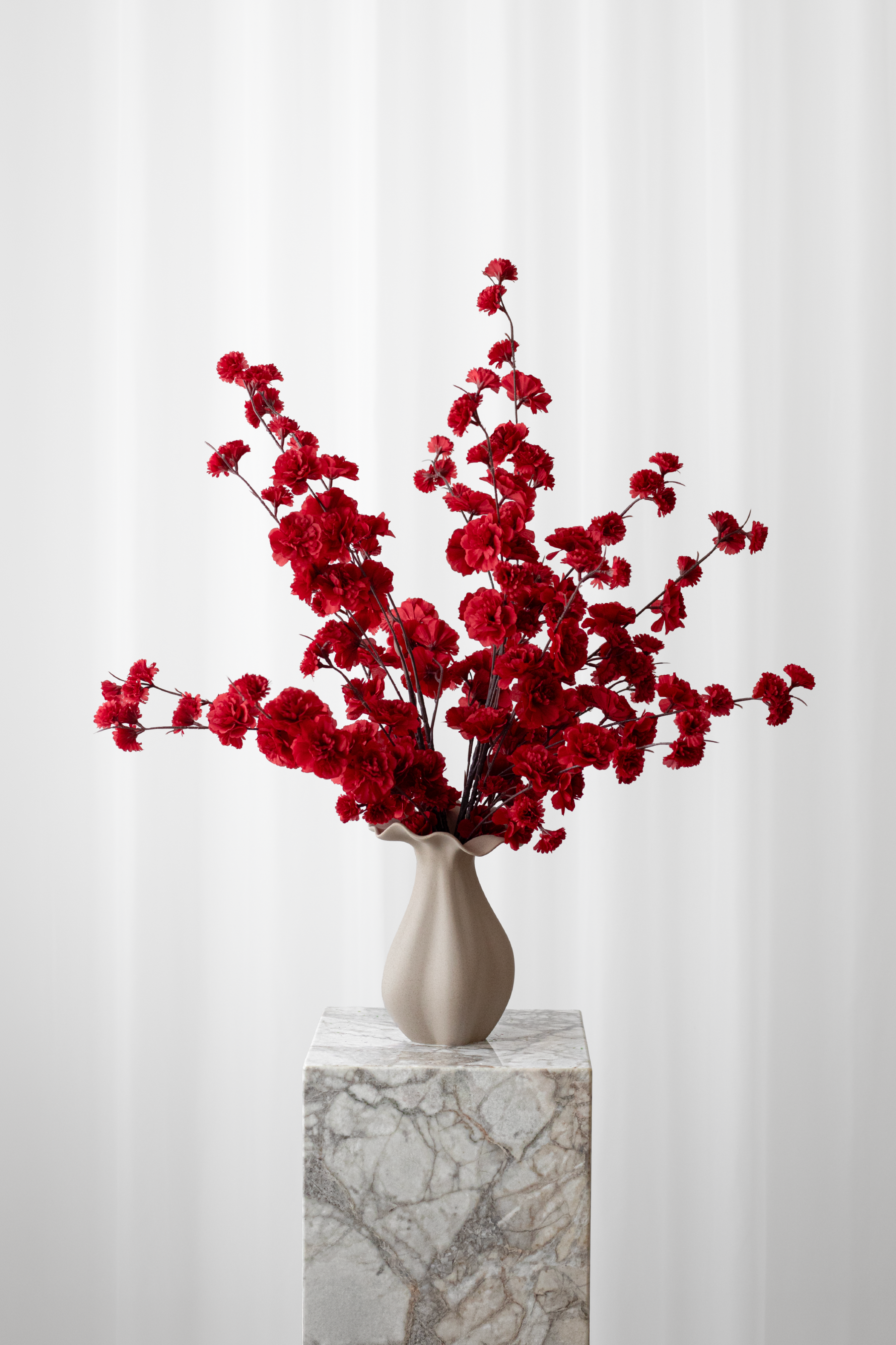 Sommerlig buket af røde kirsebærgrene. Den kunstige buket med naturtro detaljer er stylet i en keramikvase.