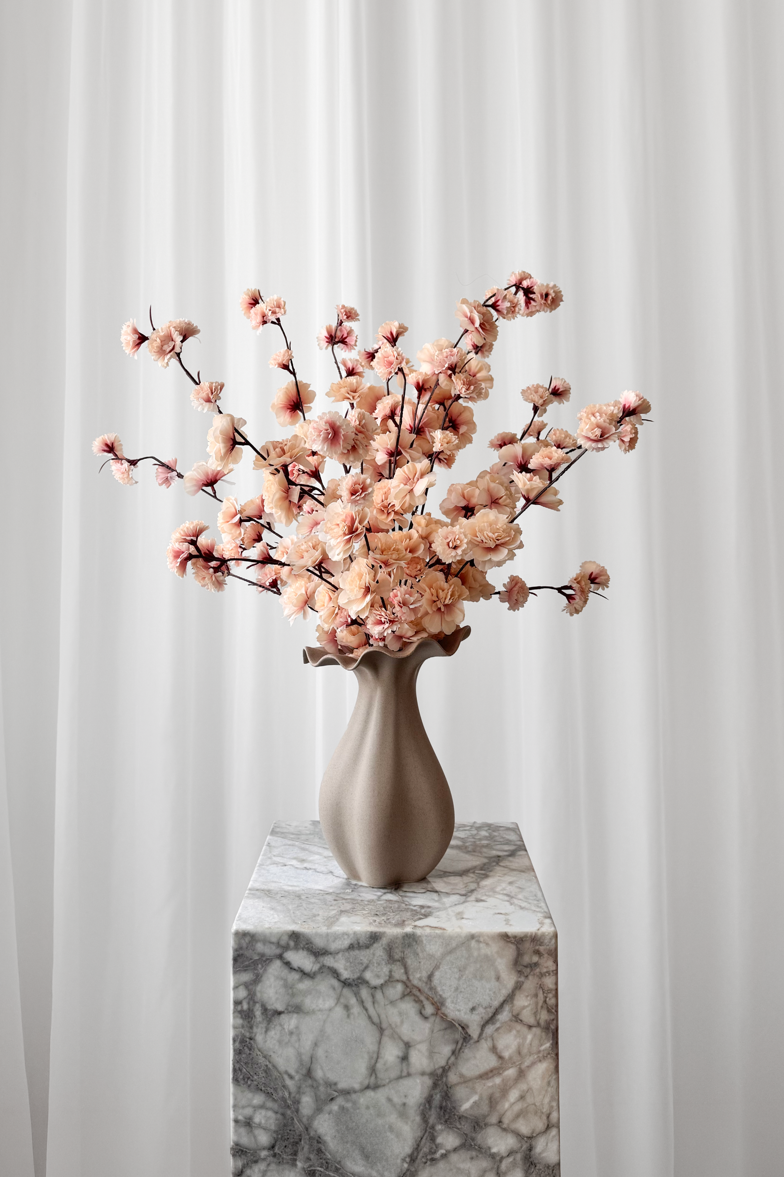 Naturtro kunstige kirsebærgrene stylet i en keramikvase.