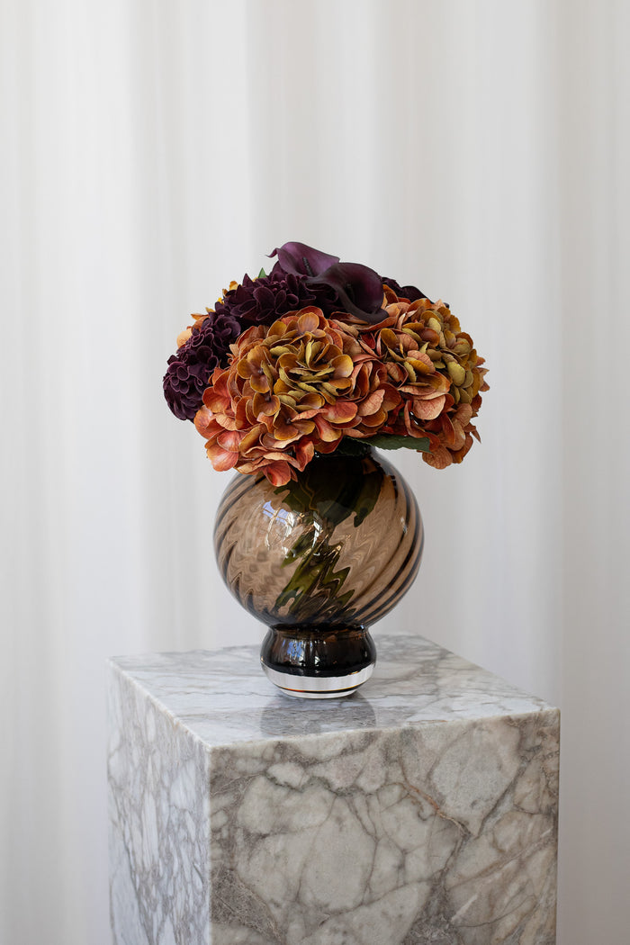 Rund buket med hortensia og calla liljer i orange og bordeaux.