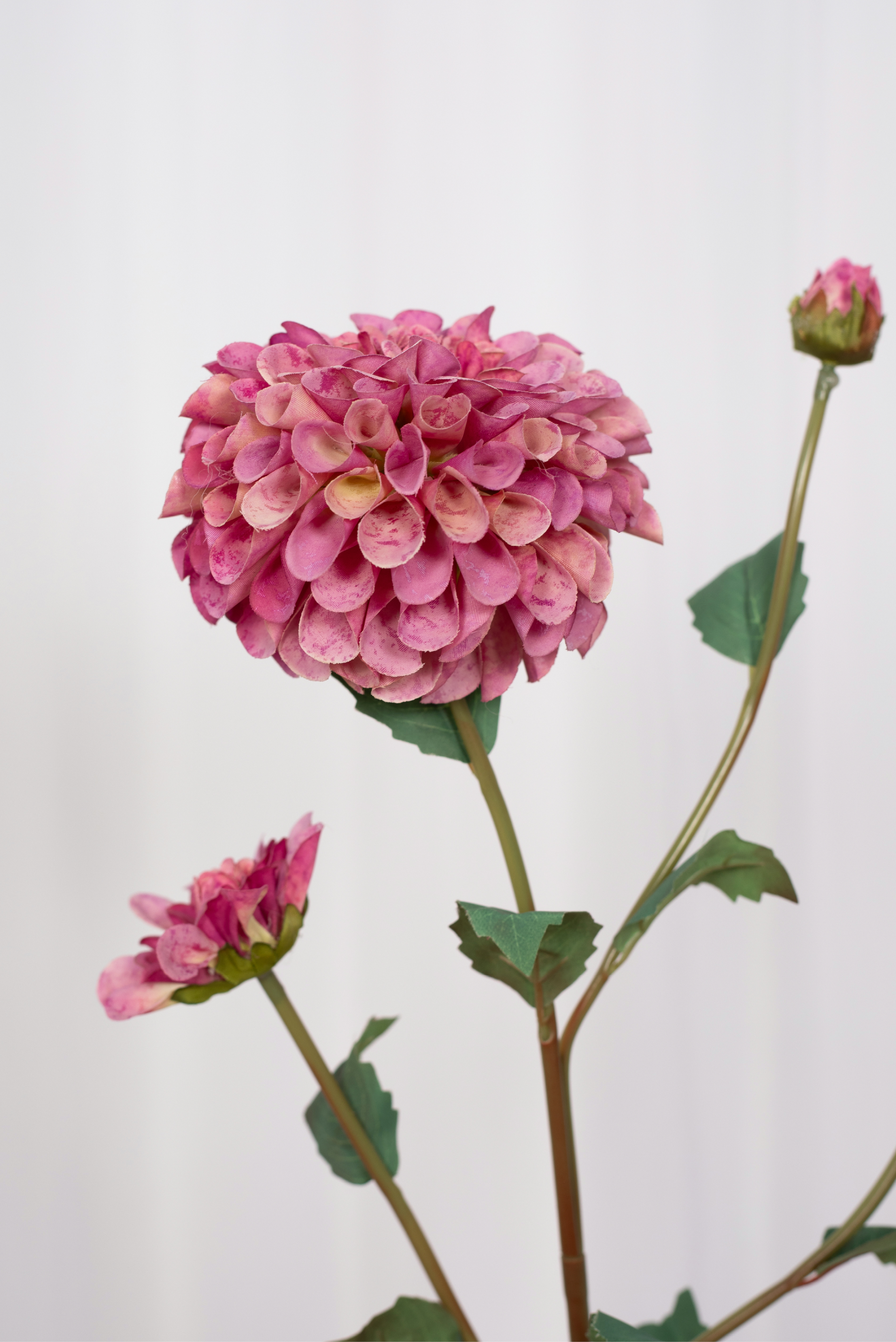 Kunstig dahlia i pink med grønne blade.