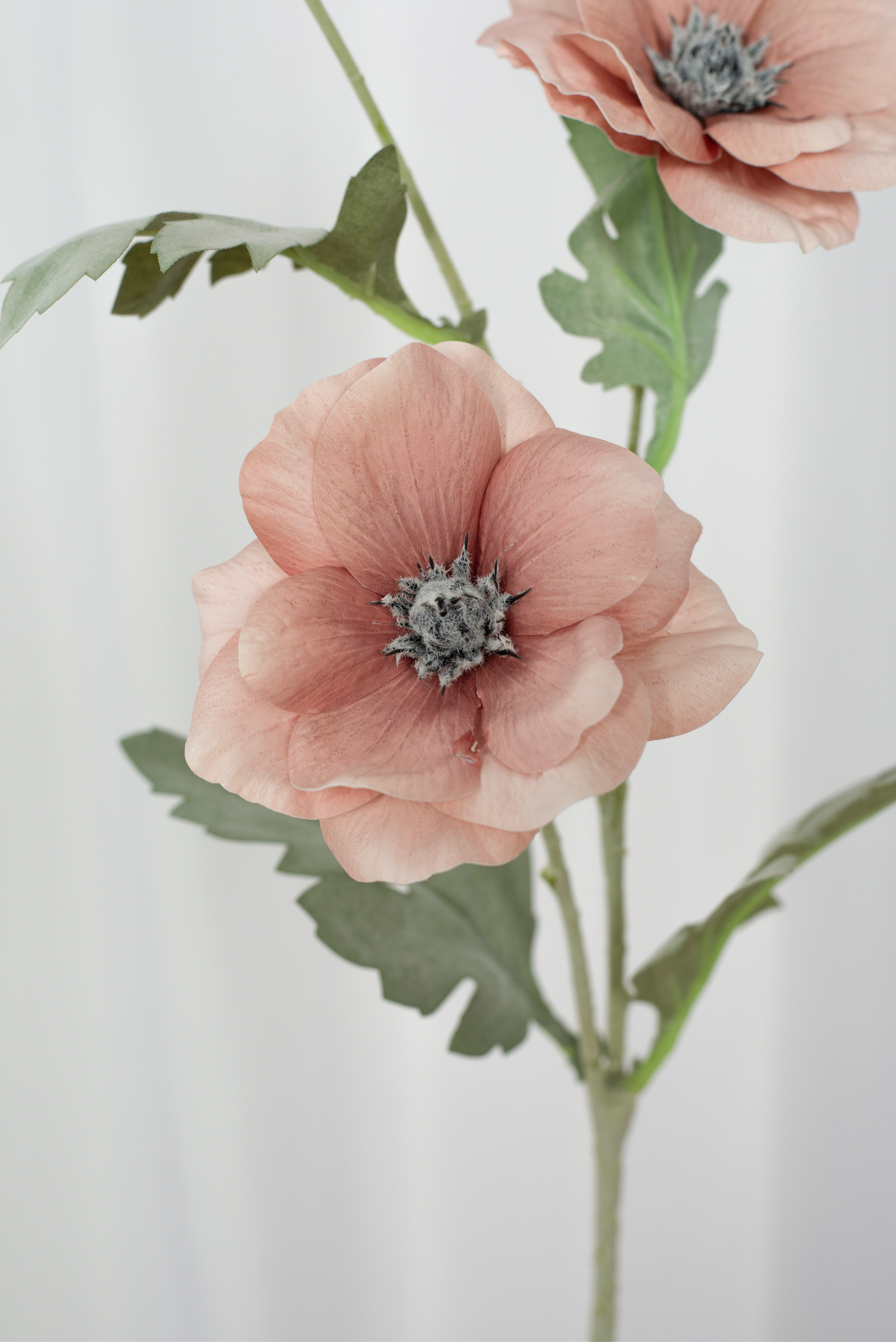 Detaljebillede af en kunstig valmue en i en støvet rosa farve.