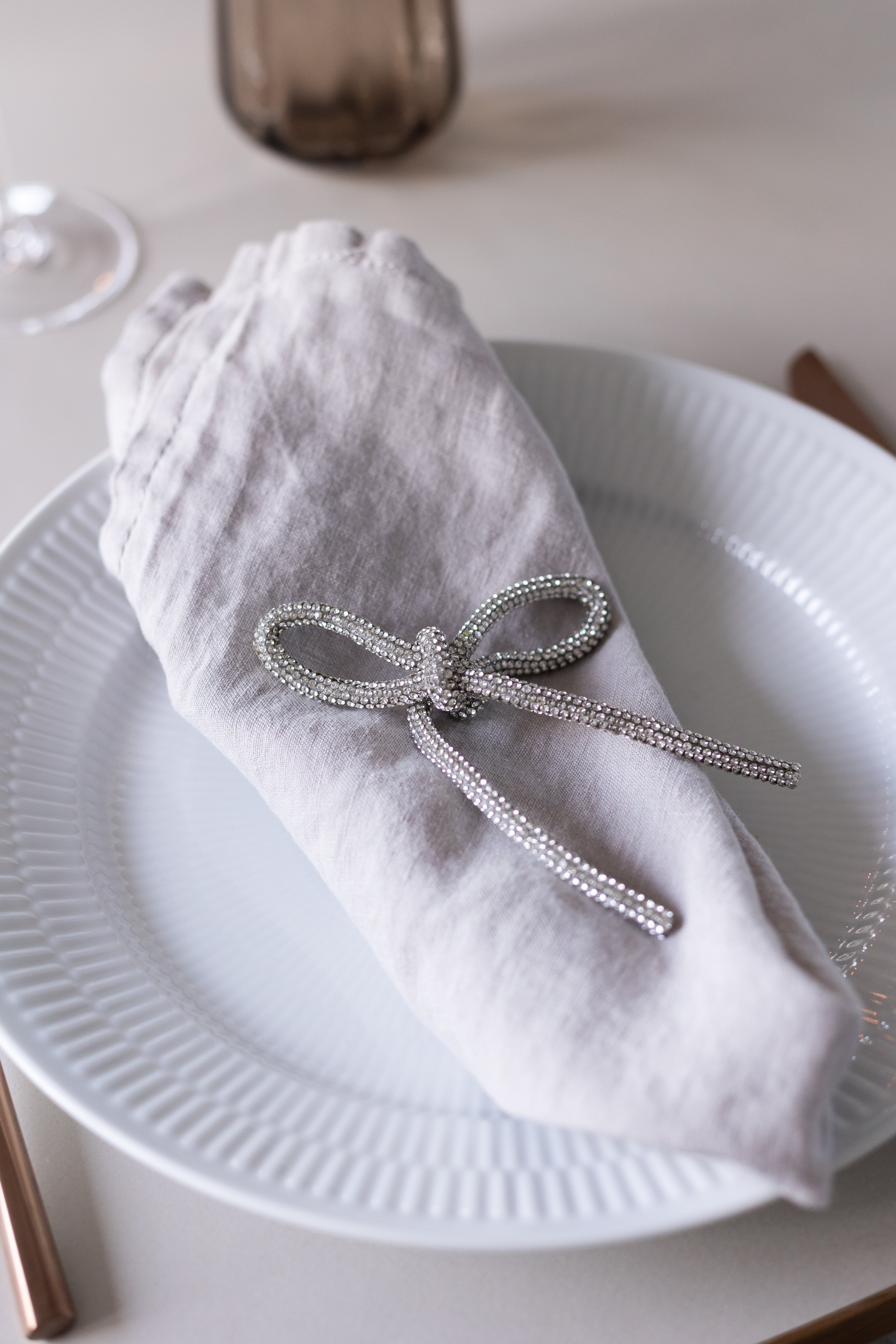 En glittersløjfe i sølv, der er brugt som en del af en smuk bordopdækning til et festligt måltid.