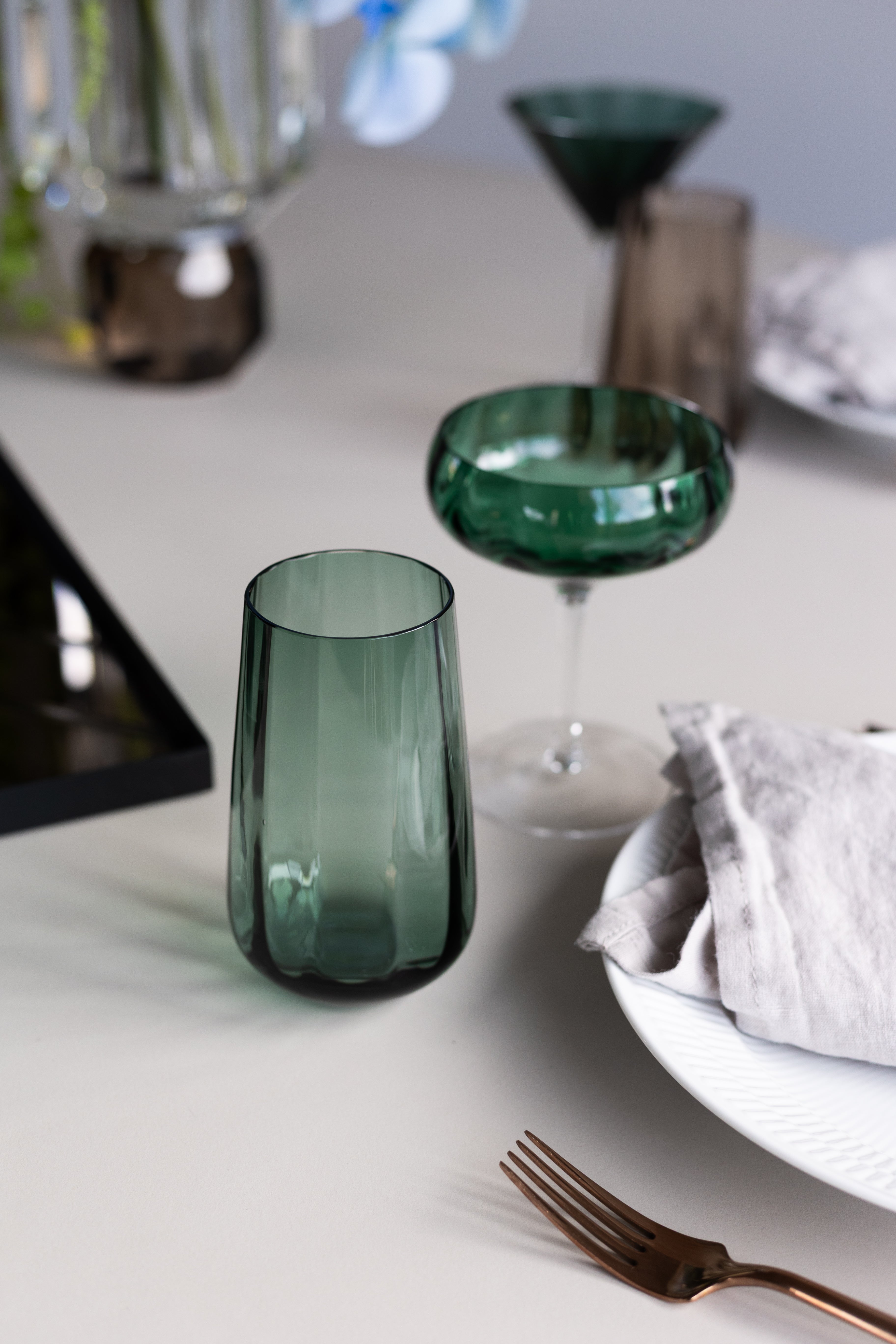 Højt drikkeglas fra Specktrum i mundblæst grønt glas med smukke riller. Glasset er en del af en smuk borddækning med andre glas fra samme Meadow kollektion.