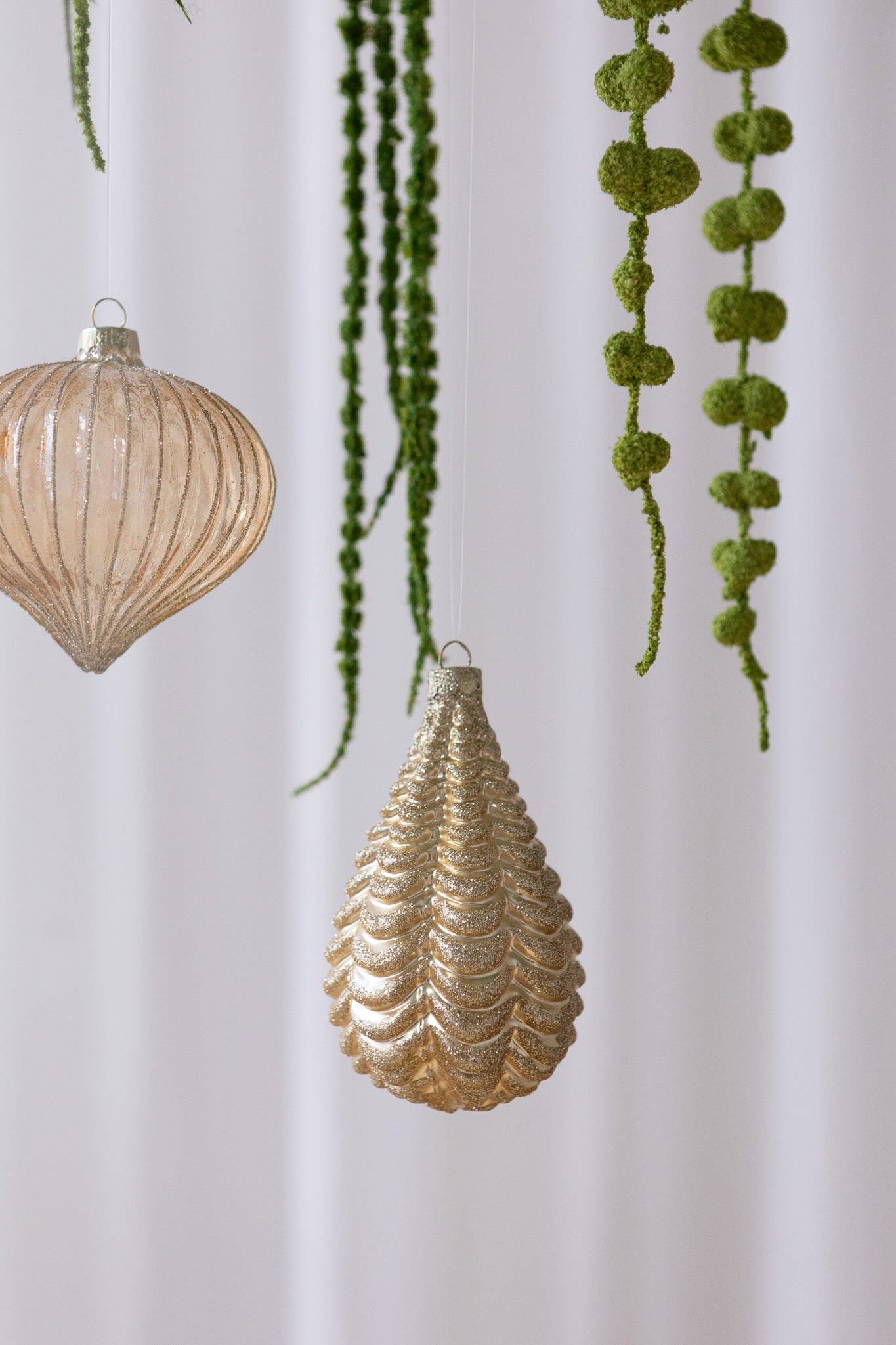 Nærbillede af Dråbeformet julekugle med koglemønster i guld med glitter