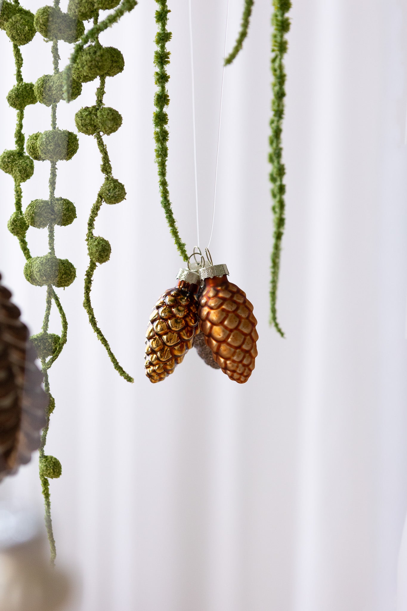 Nærbillede af 3 stk kogleformede julekugler i brun/bronze