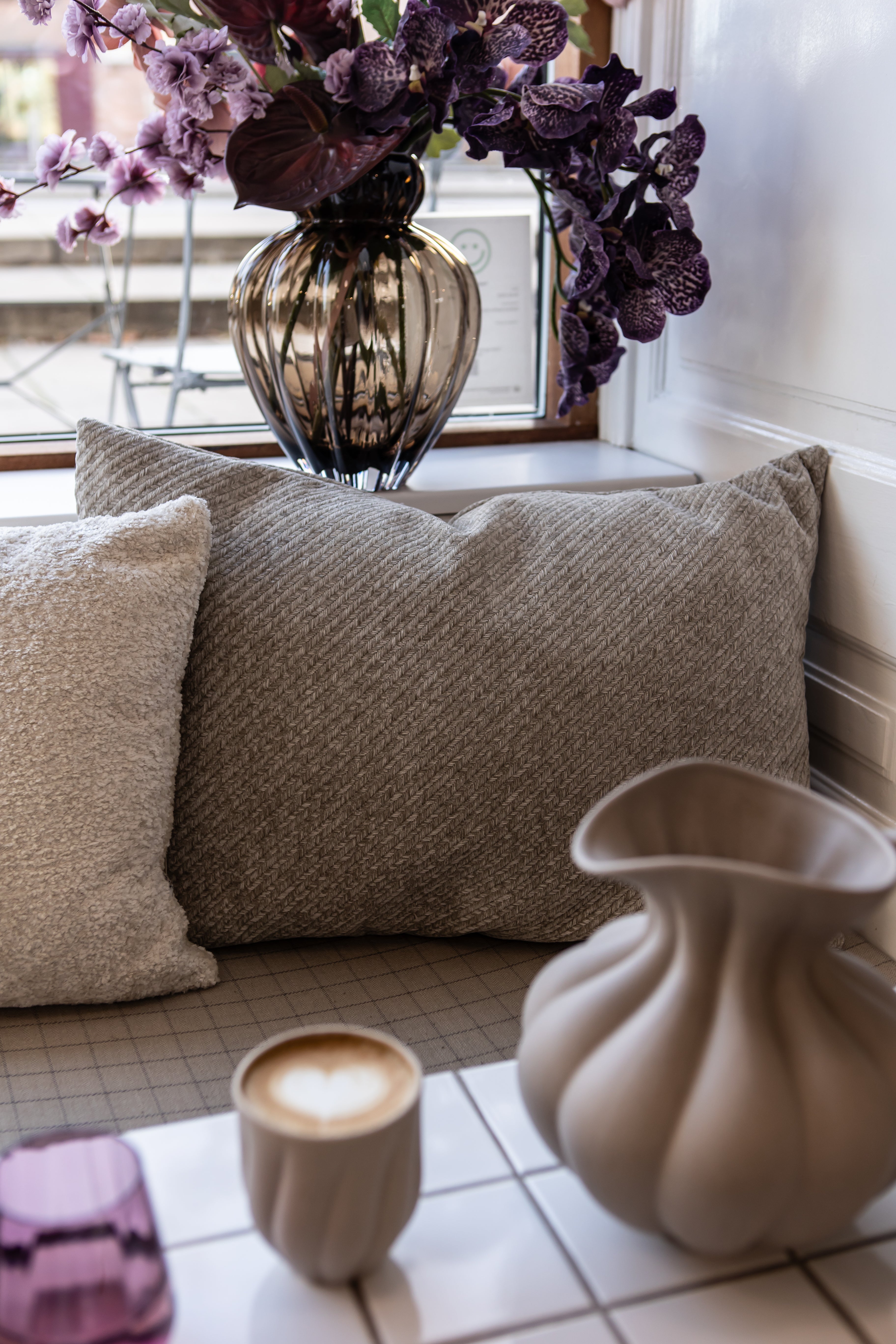 Herringbone puden i 50x70 cm i lysegrå arrangeret på enn bænk omkring spisebordet for ekstra hygge.