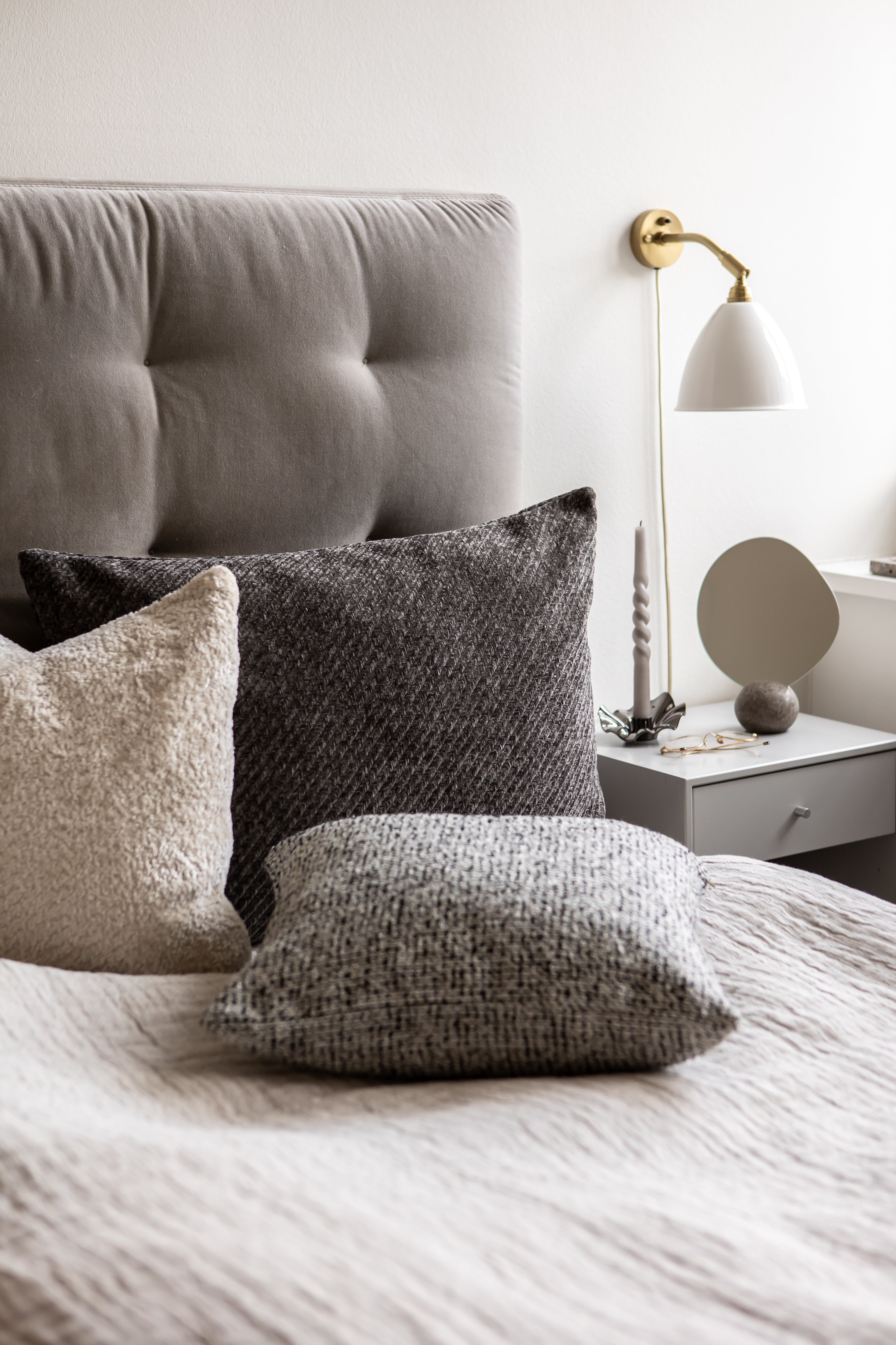 Herringbone pude fra Specktrum i mørkegrå arrangeret i en seng for at skabe en hyggelig atmosfære i soveværelset.