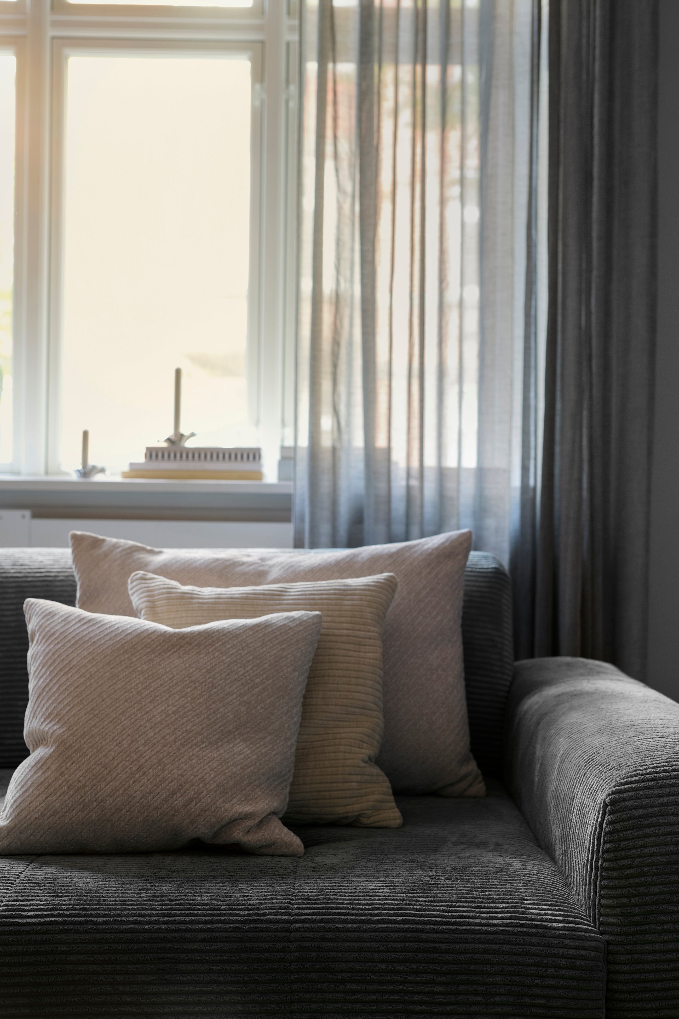 Herringbone puden arrangeret i sofa med andre puder i lyse nuancer. Puder fra Specktrum.