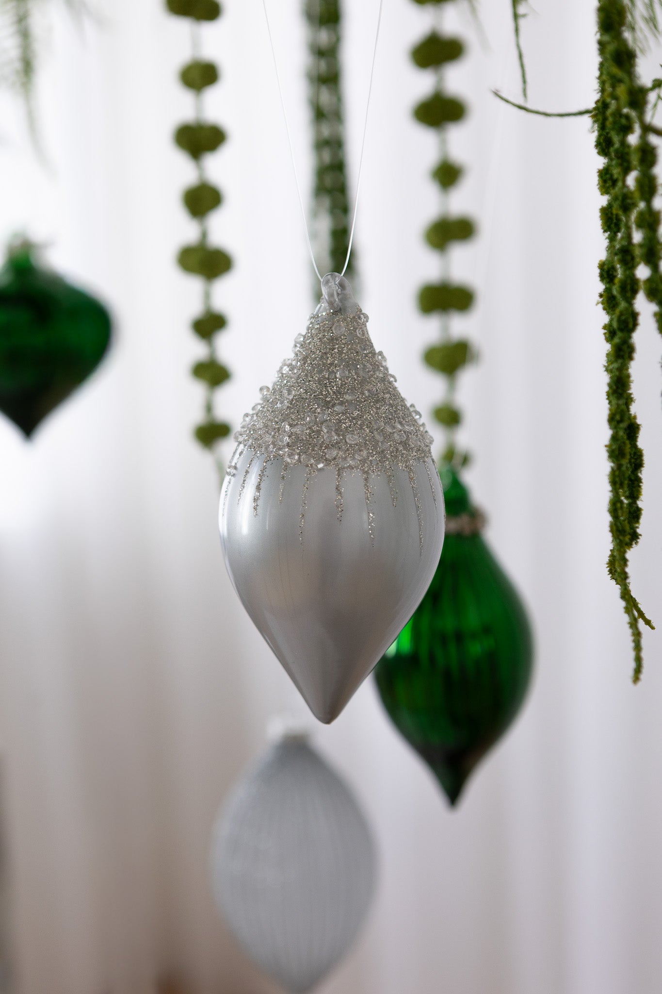 Nærbillede af Aflang julekugle med grå metallisk overflade og glimmer