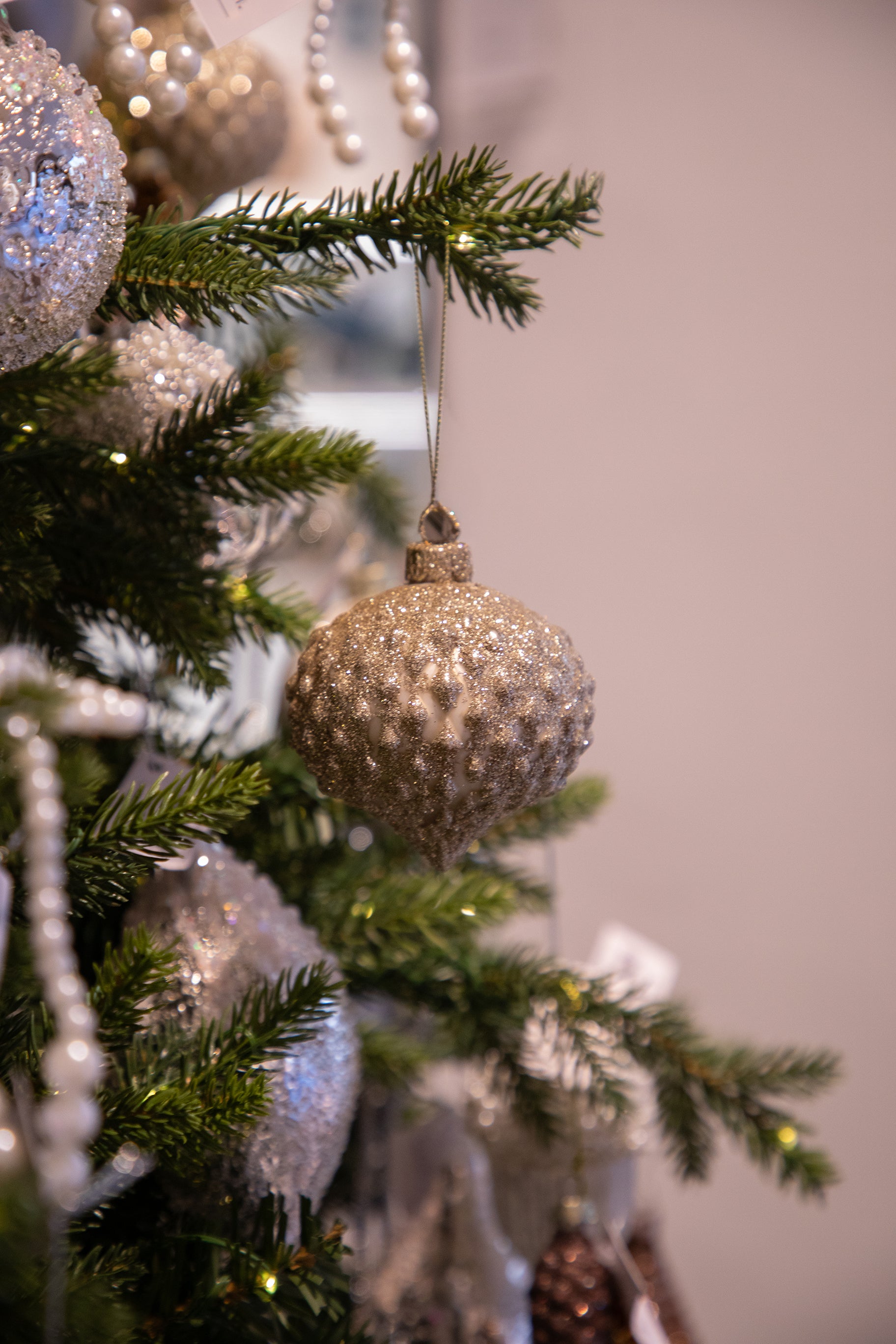 Billede af julekugle i brun/guld nuancer, der hænger på et juletræ.