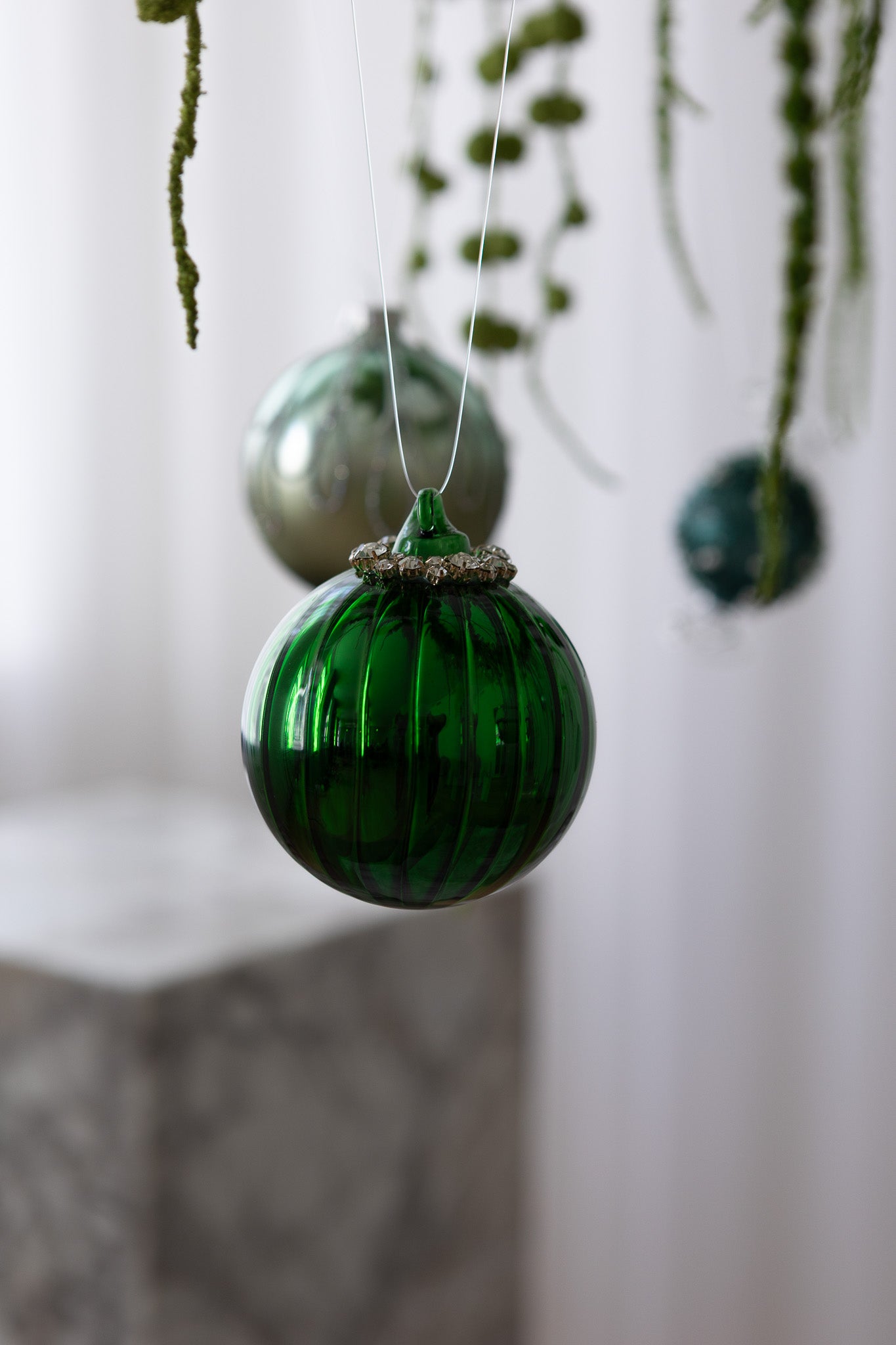 Nærbillede af Rund julekugle i grøn med linjer og krystaller i toppen