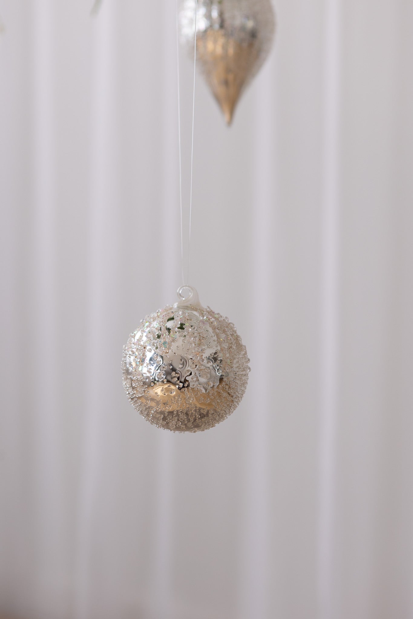 Nærbillede af Rund julekugle i sølv med frostlignende tekstur og glitter detaljer