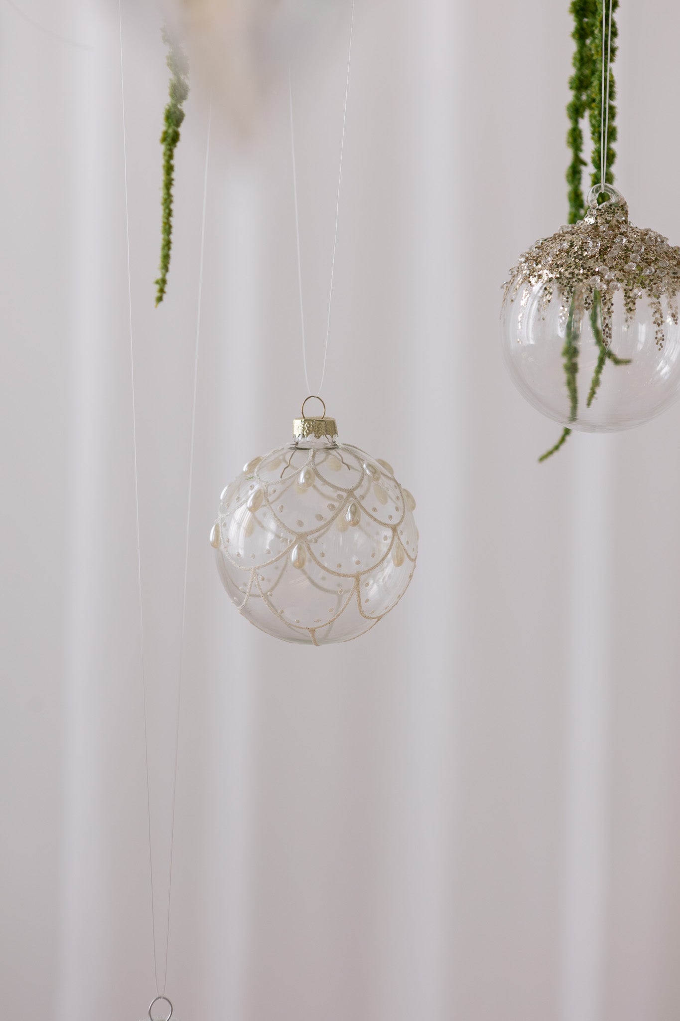 Nærbillede af Rund julekugle i klar glas med mønster i hvid glitter og perler