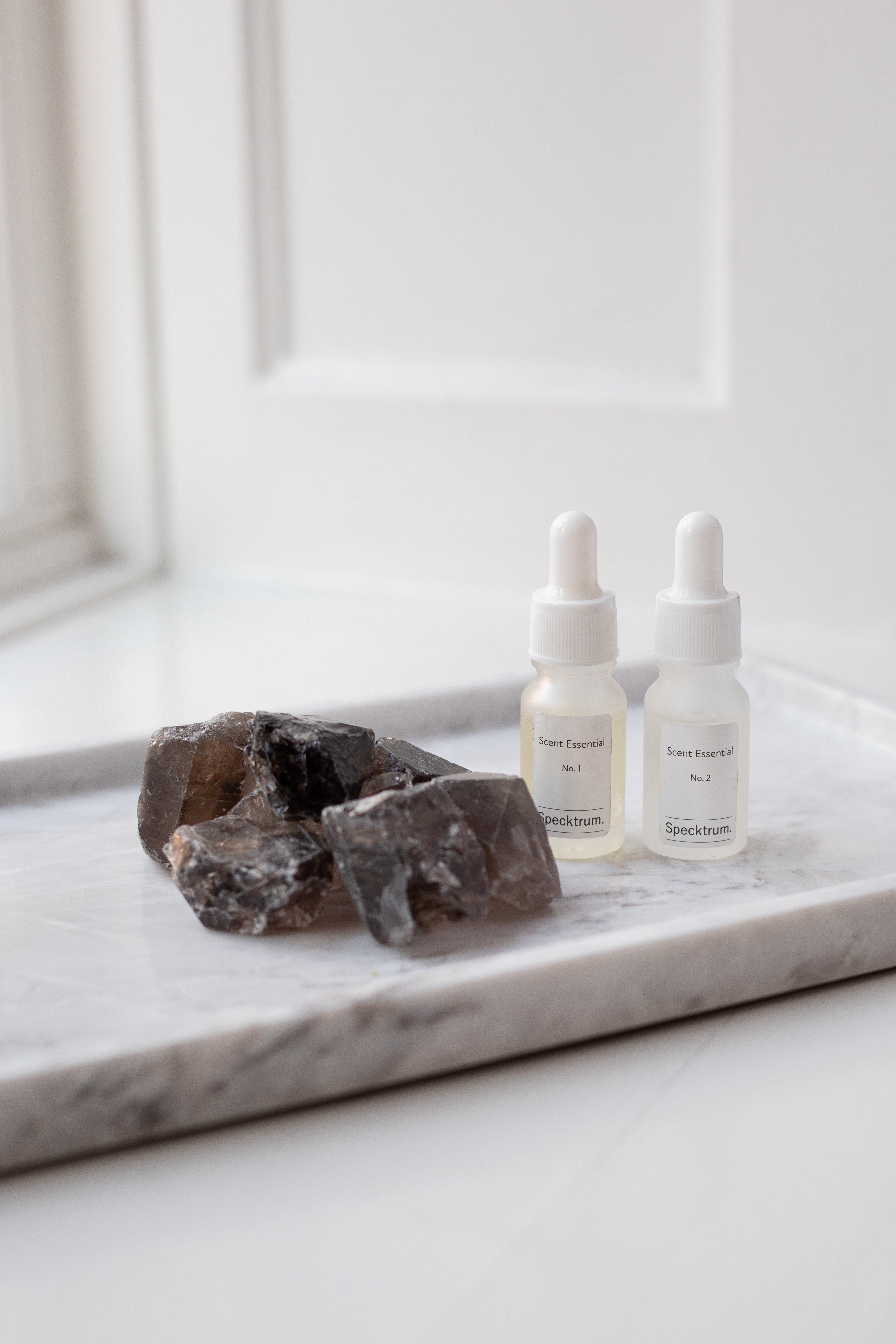 Brune krystalsten, der ligger på en marmorbakke, ved siden af står Specktrum scent til duftlys