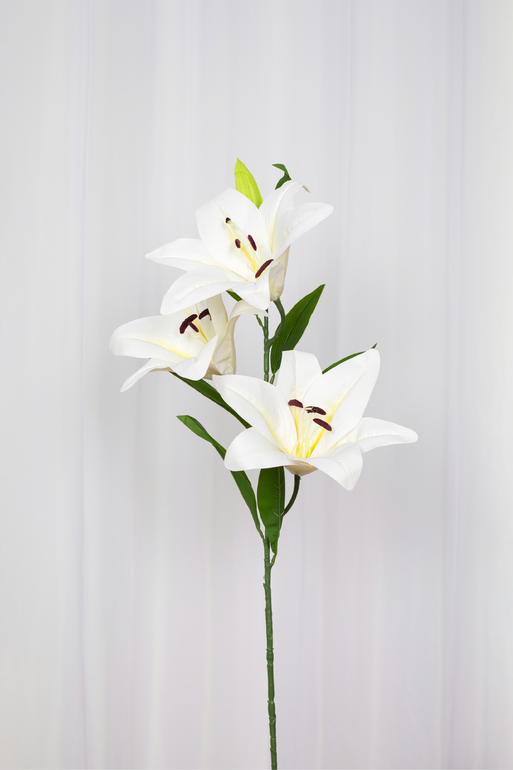 Stor kunstig hvid lilje med tre blomsterhoveder på.