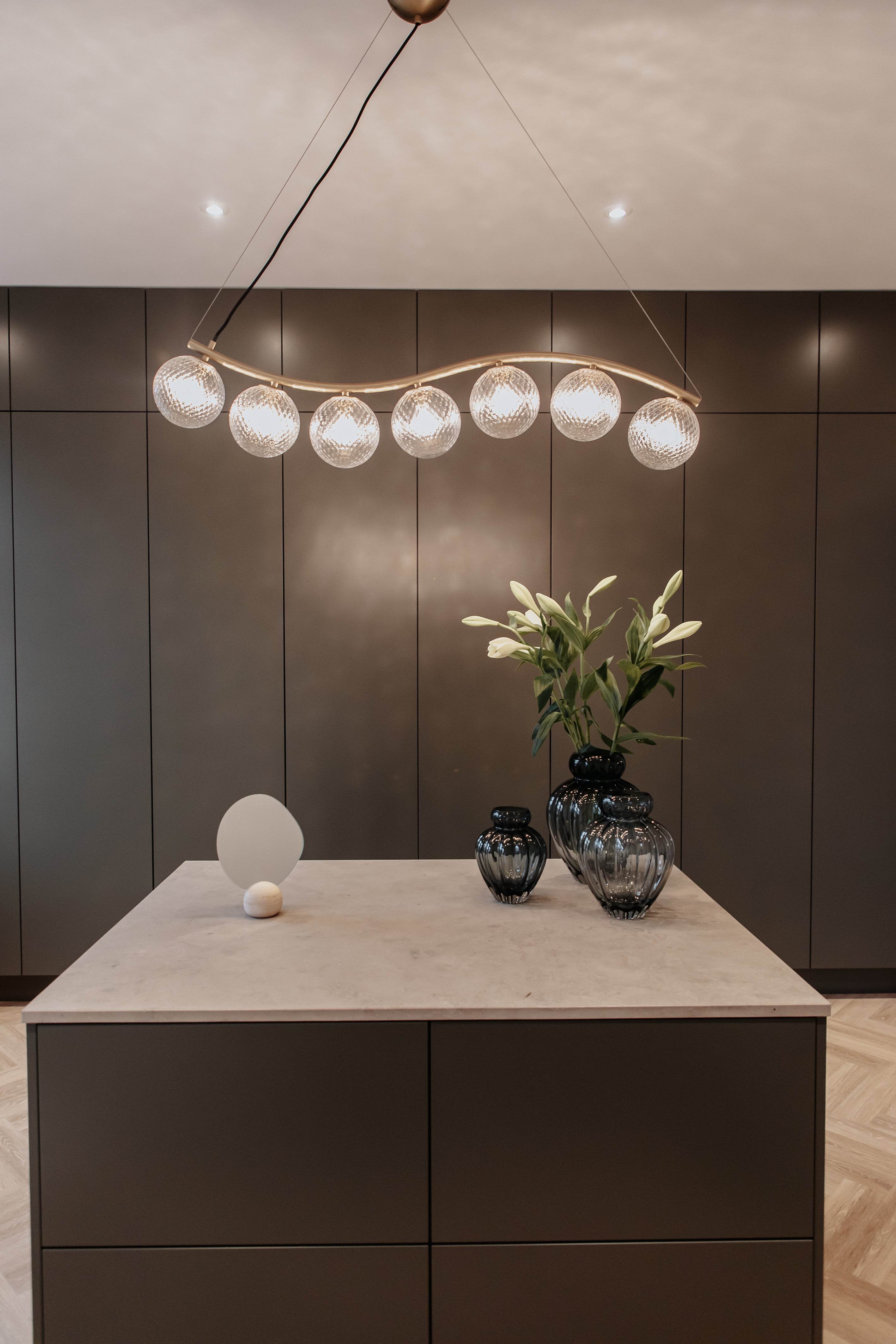 Liva 7 lysekronen, der hænger i et walk-in closet. Stylet sammen med vaser og et bordspejl fra Specktrum.