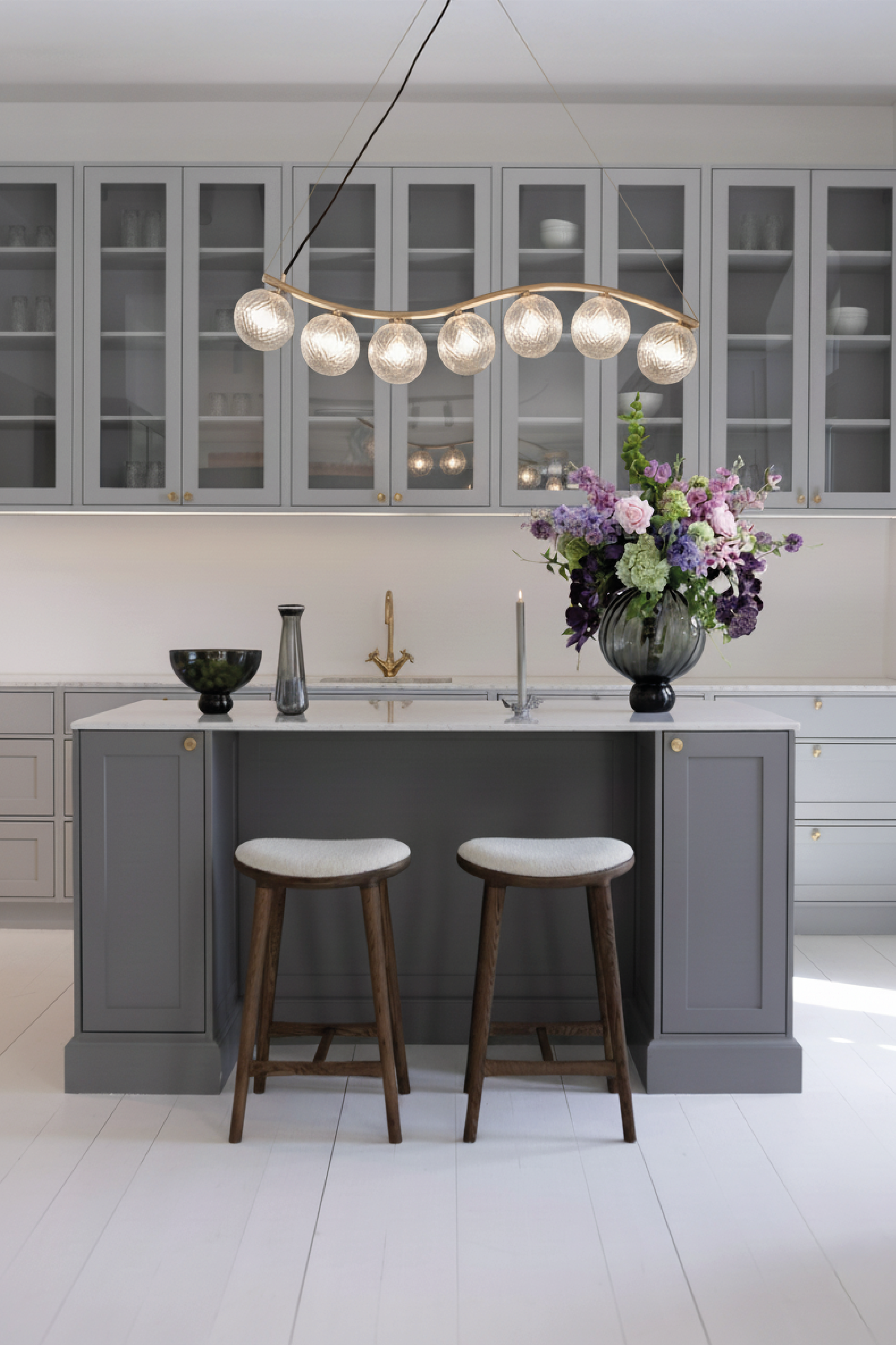 Liva 7 lysekronen, der er hængt over en køkkenø. Køkkenet er stylet med lampen, vaser og andre designs fra Specktrum.