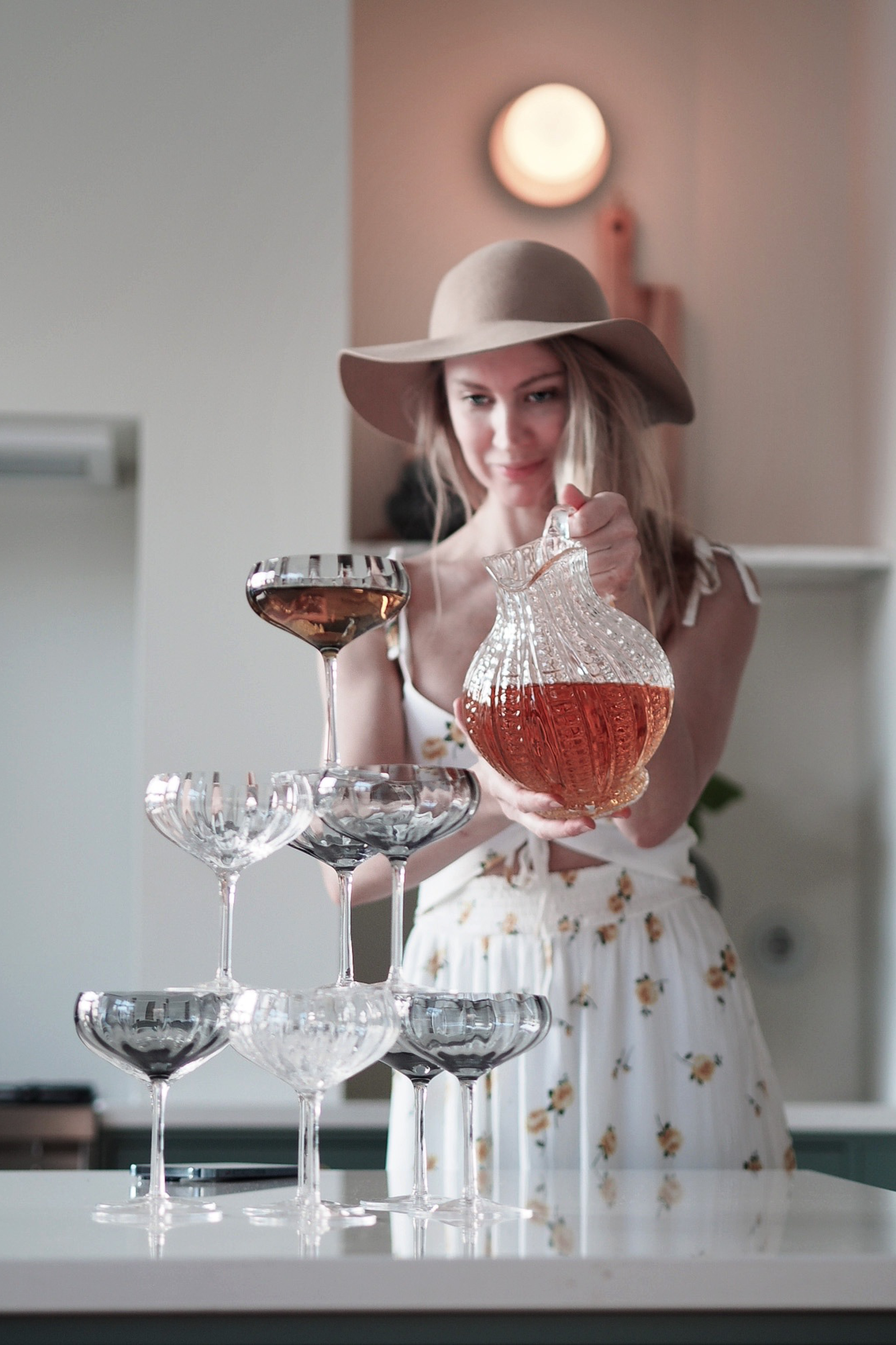 Tårn af cocktailglas, hvor en kvinde hælder drinks ned over champganetårnet.