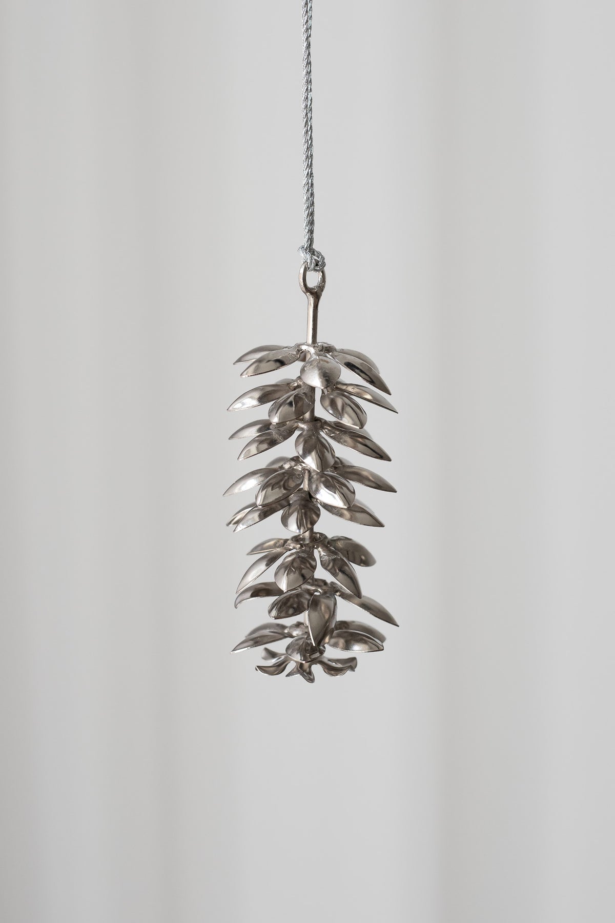 Metal grankogle, der hænger. Metalkoglen er sølv med fine detaljer.