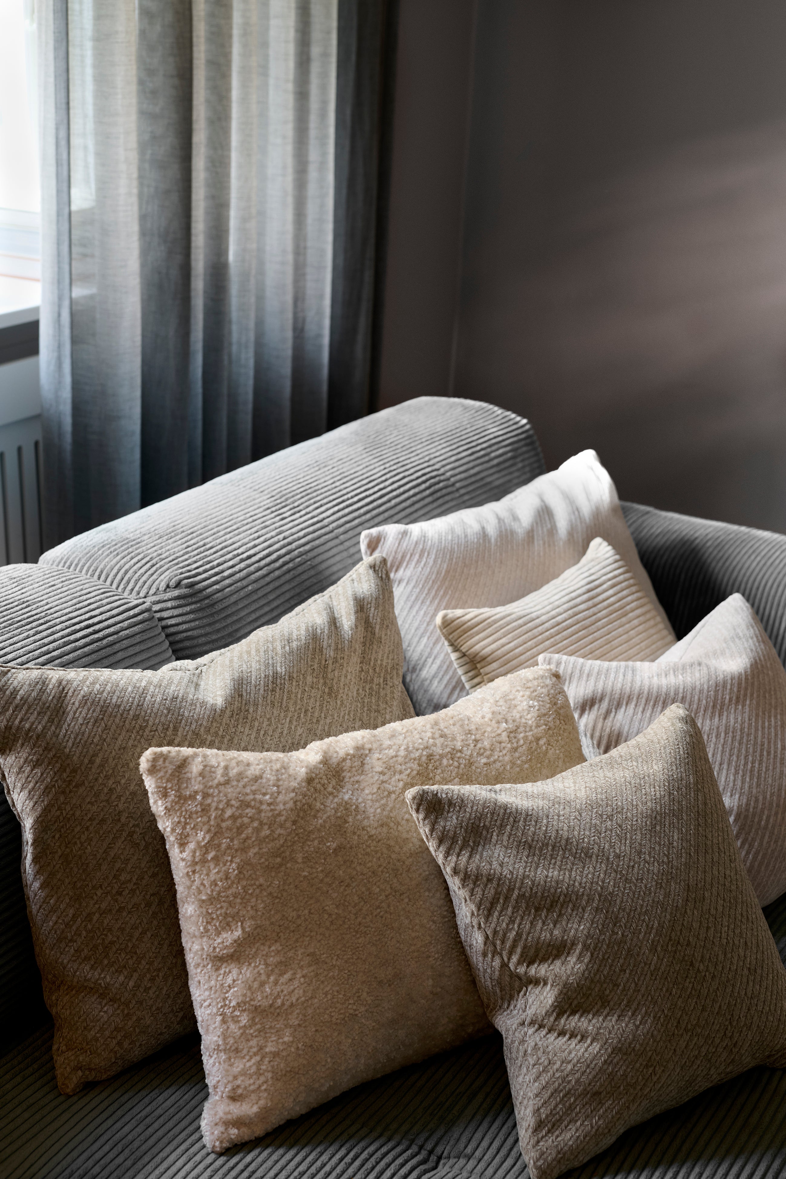 Herringbone pude fra Specktrum i farven lysegrå. Puden er arrangeret sammen med andre pude i samme lyse nuancer i en sofa.