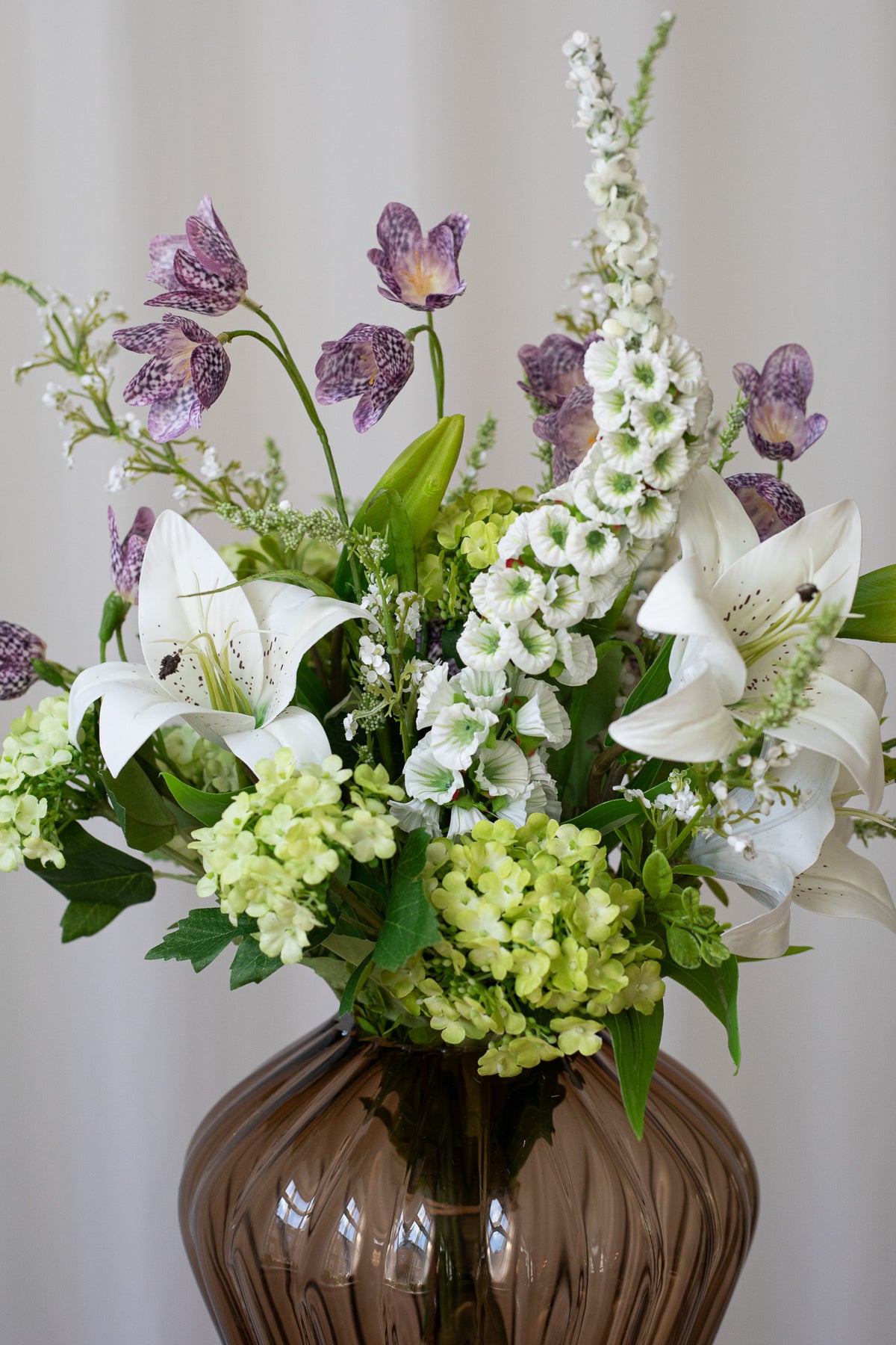 Nærbillede af kunstig buket med naturtro detaljer. Buketten bestyr af liljer, hortensia og klokkeblomster.