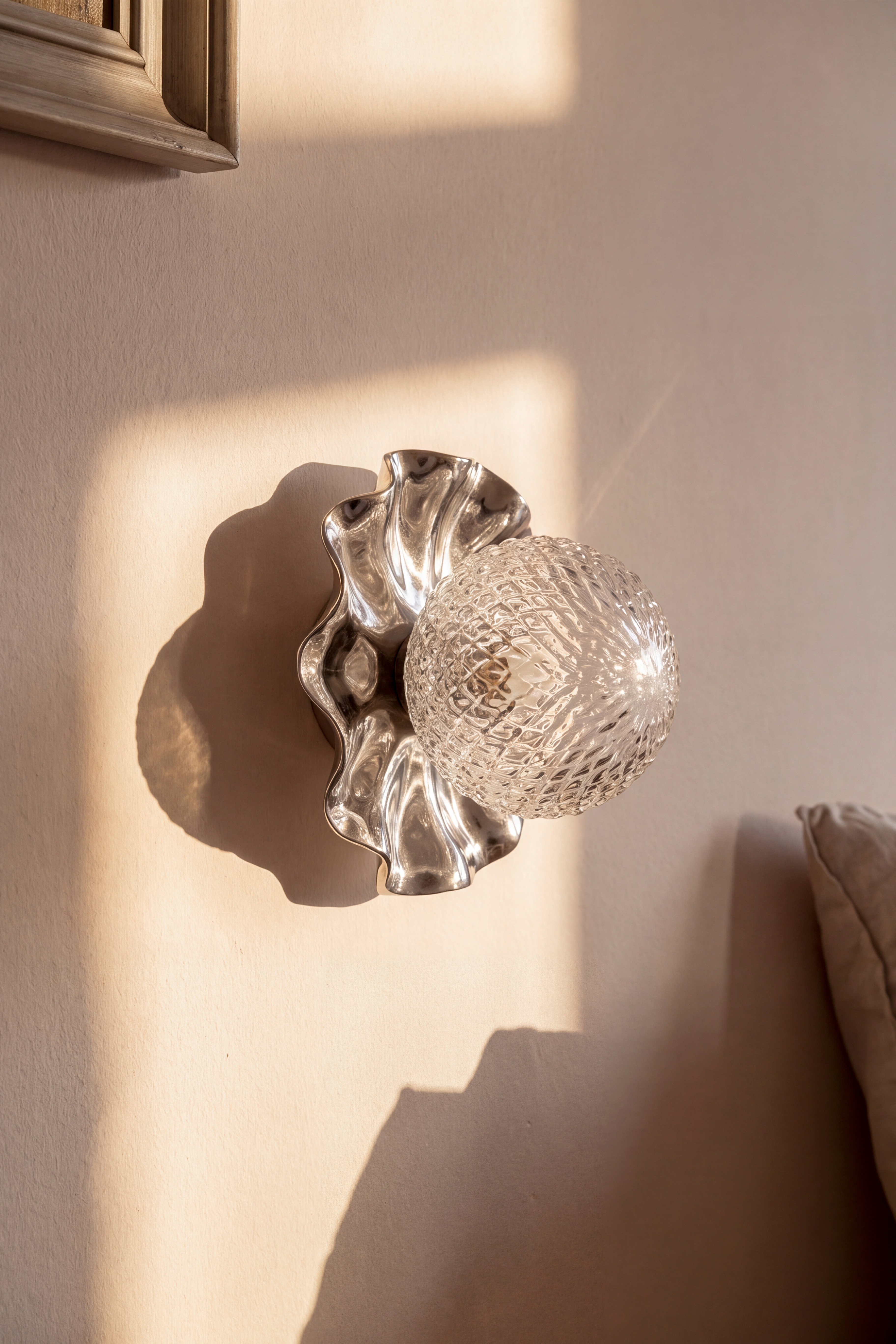 Nærbillede af Lea lampen med sine bølgende former i metal, blanke krom overflade og klare glaskuppel med harlequin mønster. Lampen er fra Specktrum.