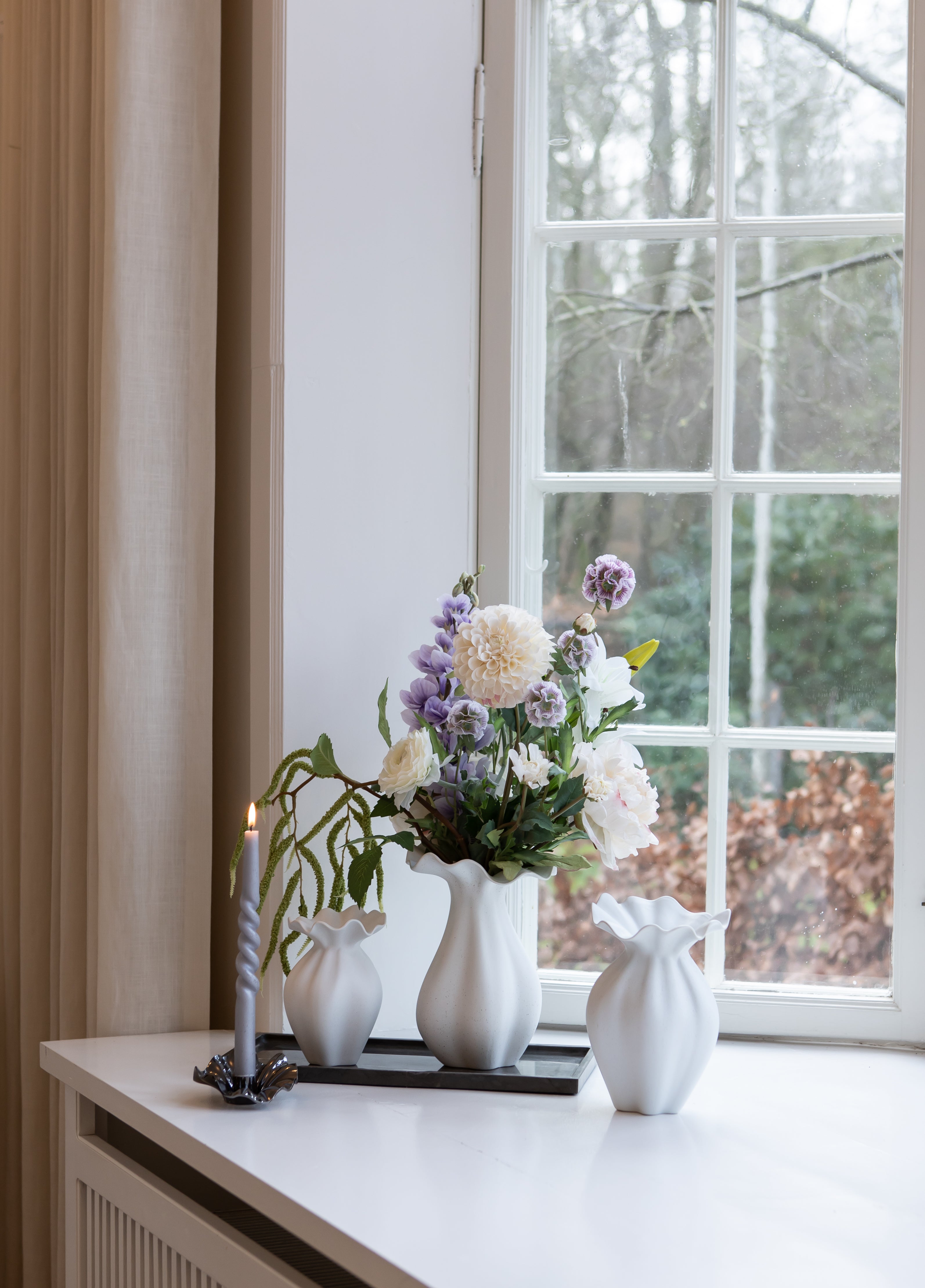 Nellie vaser I off white stylet på en marmorbakke og med en metal lysestage med samme organiske former.