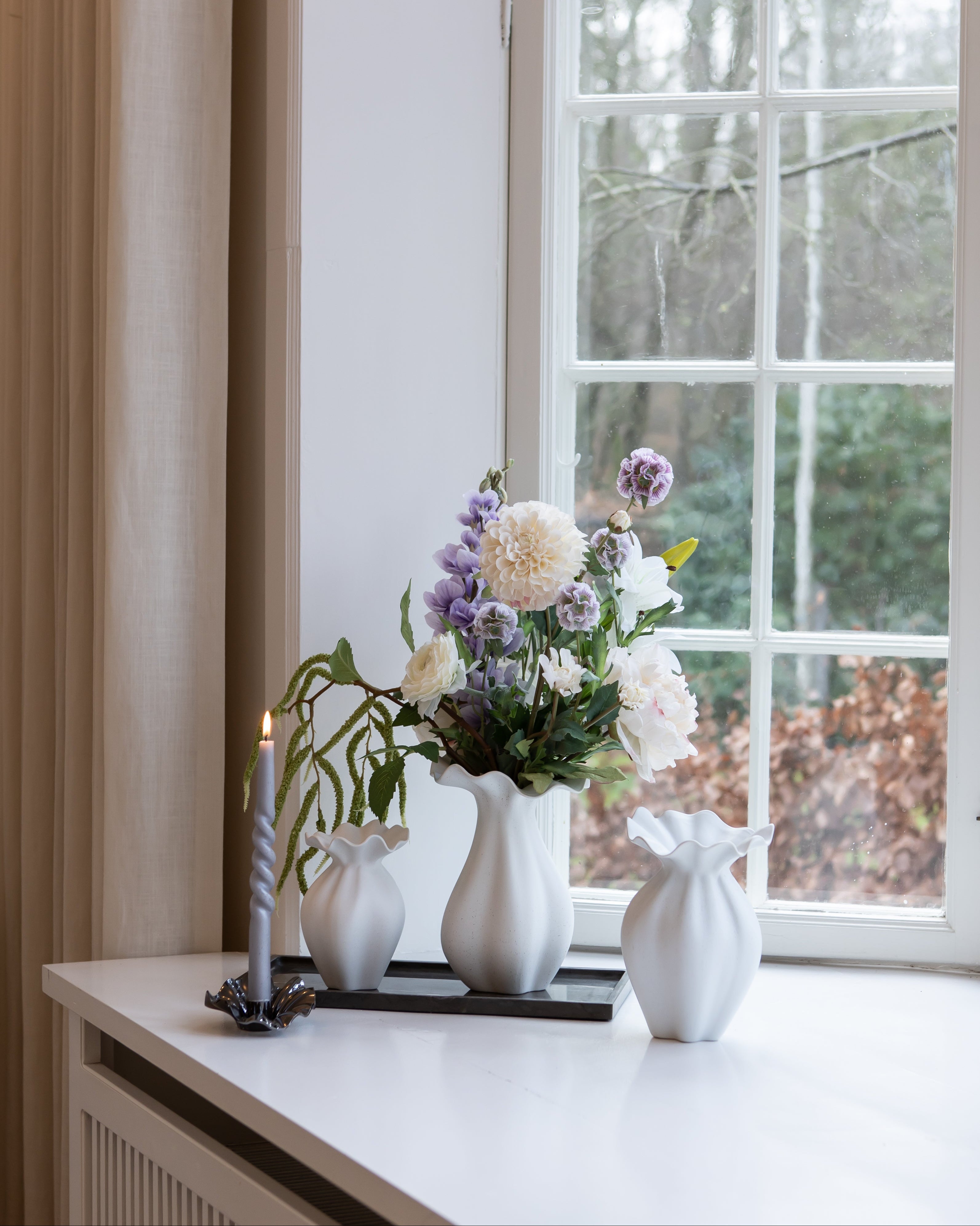 Nellie vaser I off white stylet på en marmorbakke og med en metal lysestage med samme organiske former.