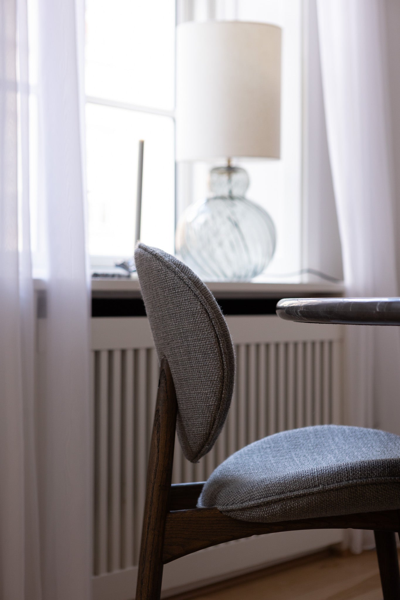 FSC-certificeret spisebordsstol fra Specktrum i mørkolieret egetræ med gråt tekstil, der står ved et mormor spisebord.