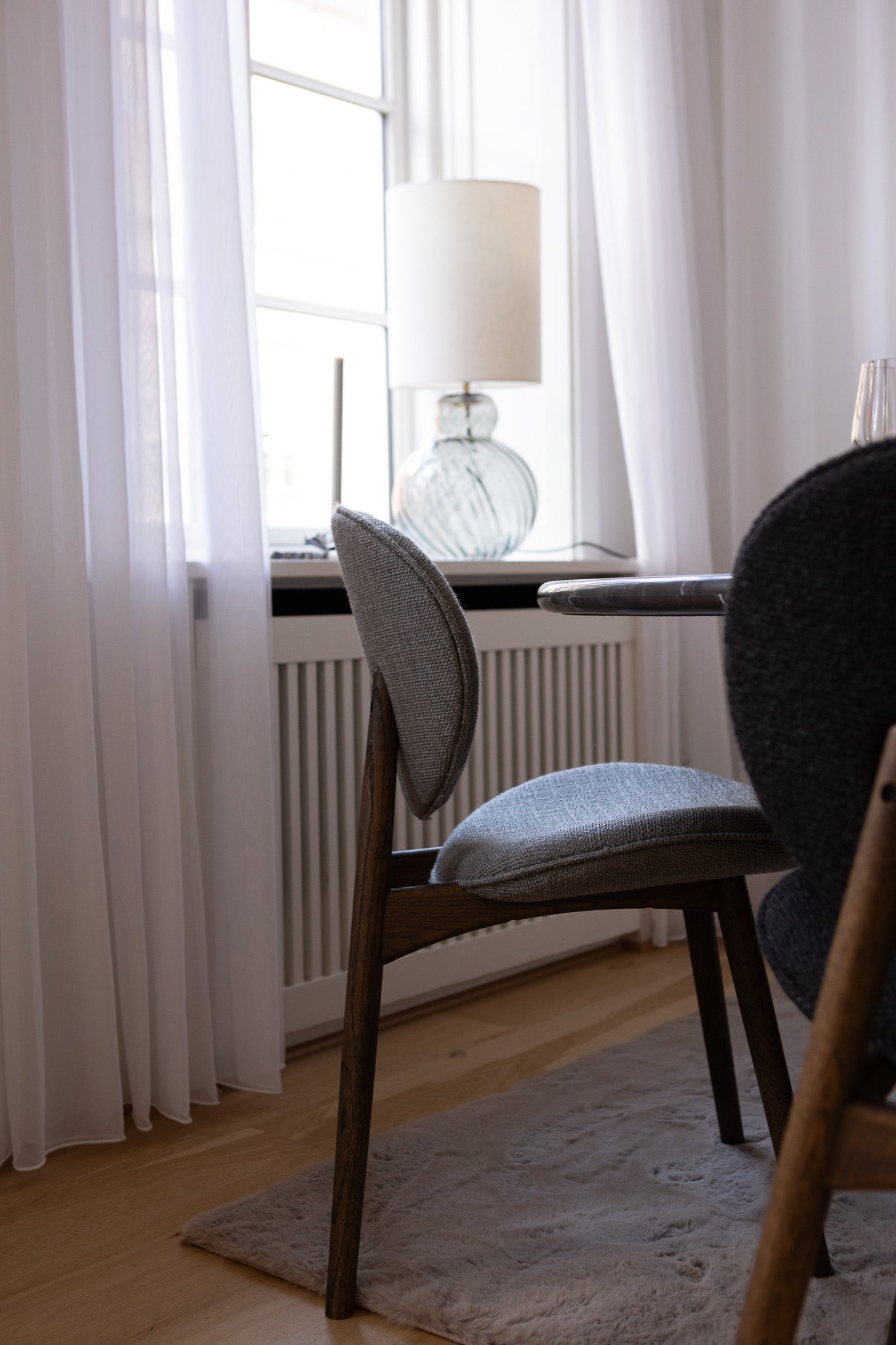 FSC-certificeret spisebordsstol fra Specktrum i mørkolieret egetræ med gråt tekstil, der står ved et mormor spisebord.