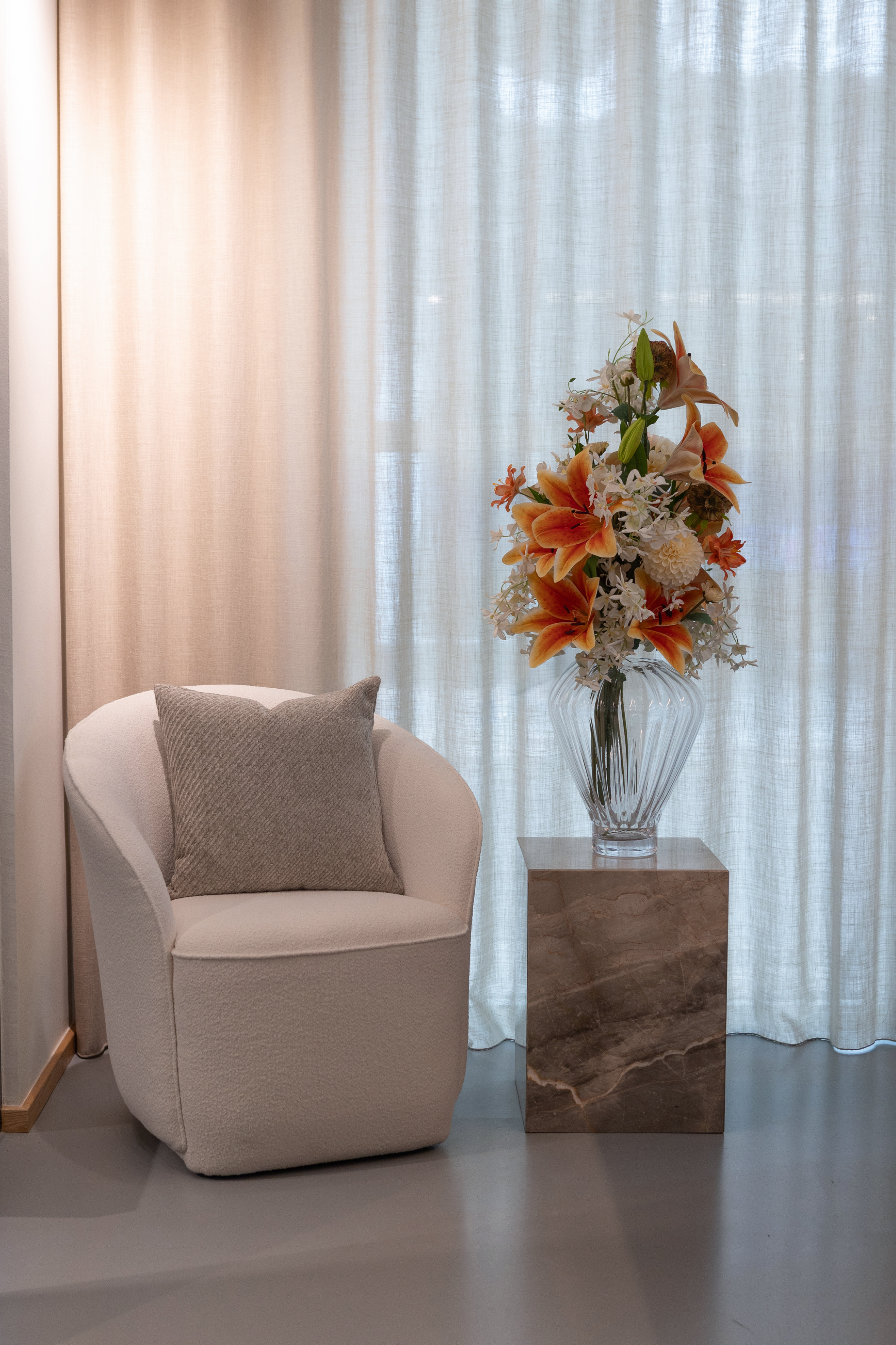 Sidebord i marmor, der står ved siden af en loungestol. PÅ sidebordet pynter en smuk buket i en vase fra Specktrum.