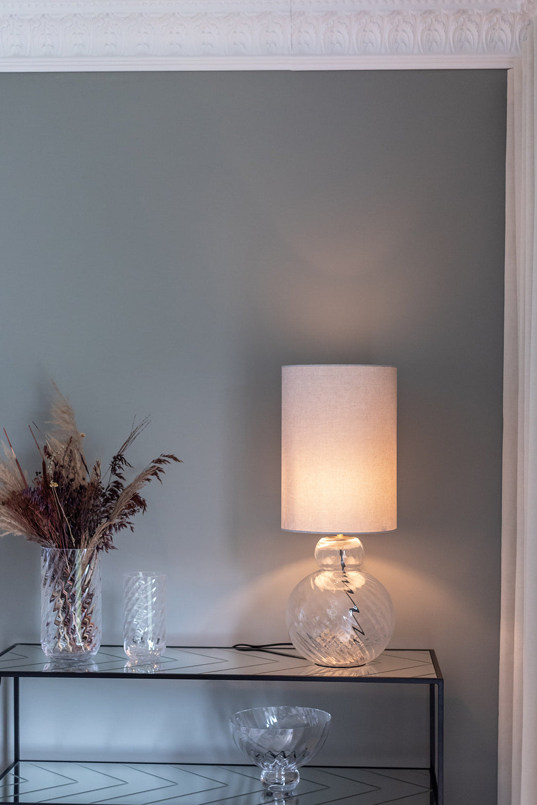 Lily bordlampe og sylvester lampeskærm. Står på en rel med meadow glas.