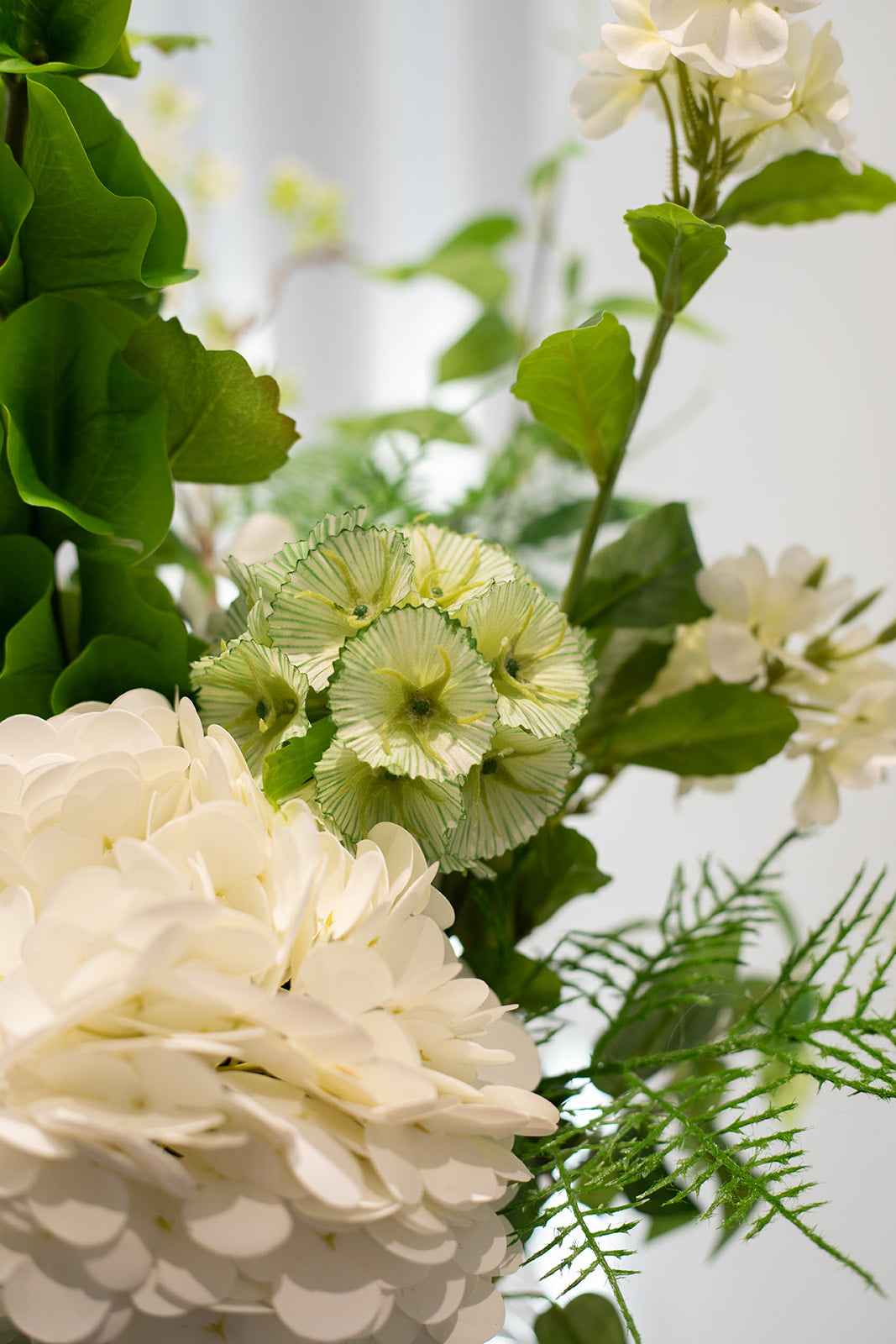 Nærbillede af kunstig buket i grønne og hvide nuancer.