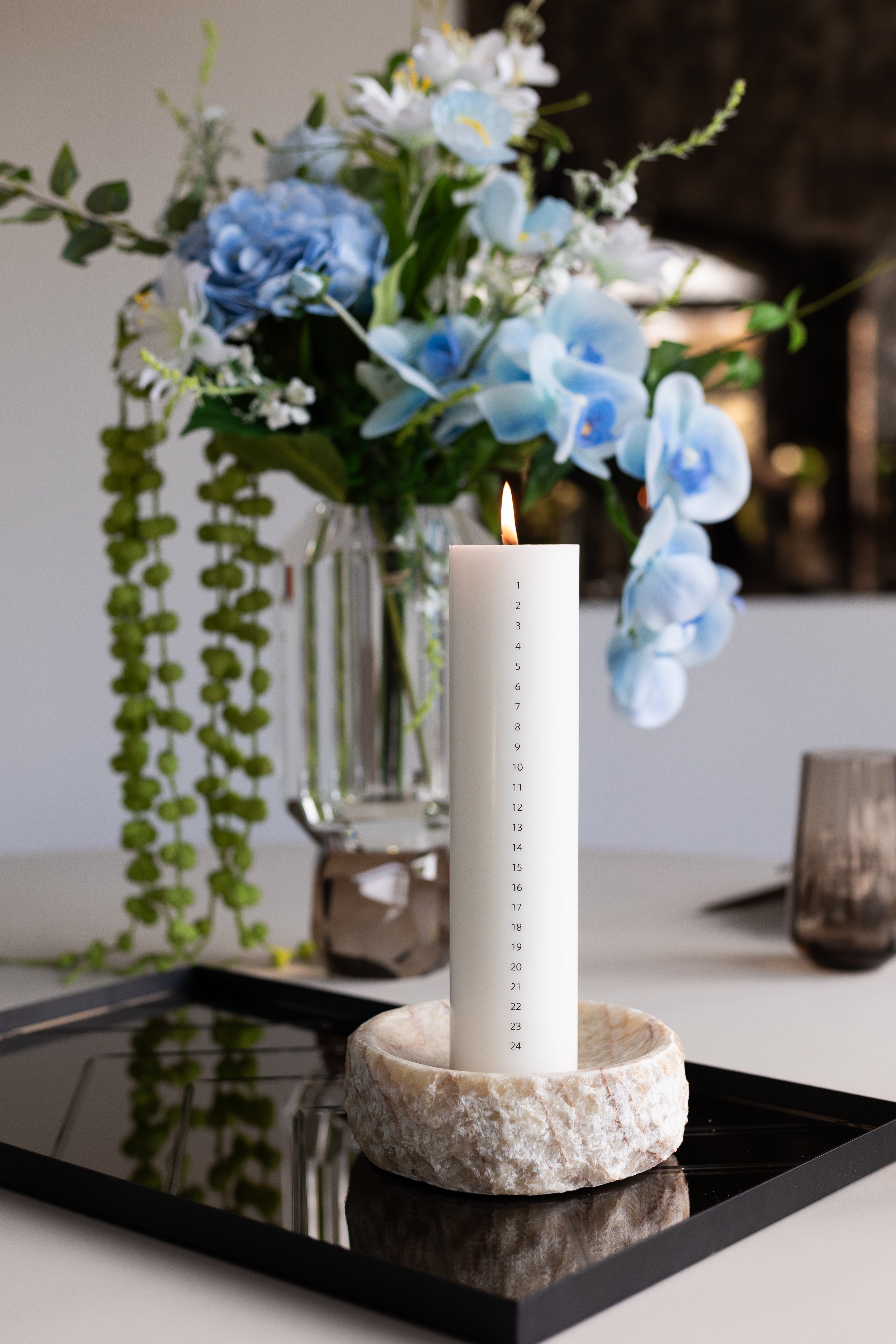 Kalenderlys fra Specktrum i hvid stylet i en ivy skål på en spejlbakke på spisebordet. Lyset er Svanemærket.