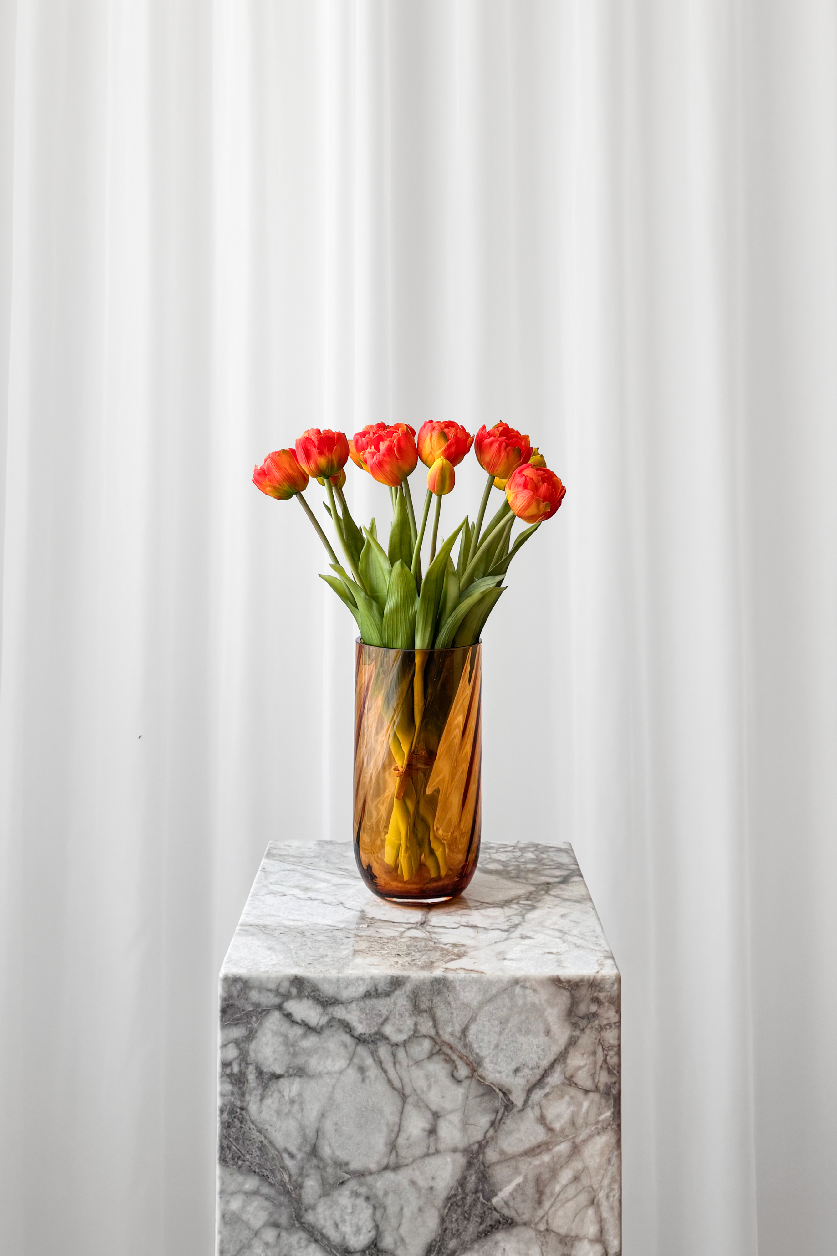 Bulet af tulipaner i orange nuancer. De naturtro kunstige blomster er stylet i en cylinder glasvase fra Specktrum.