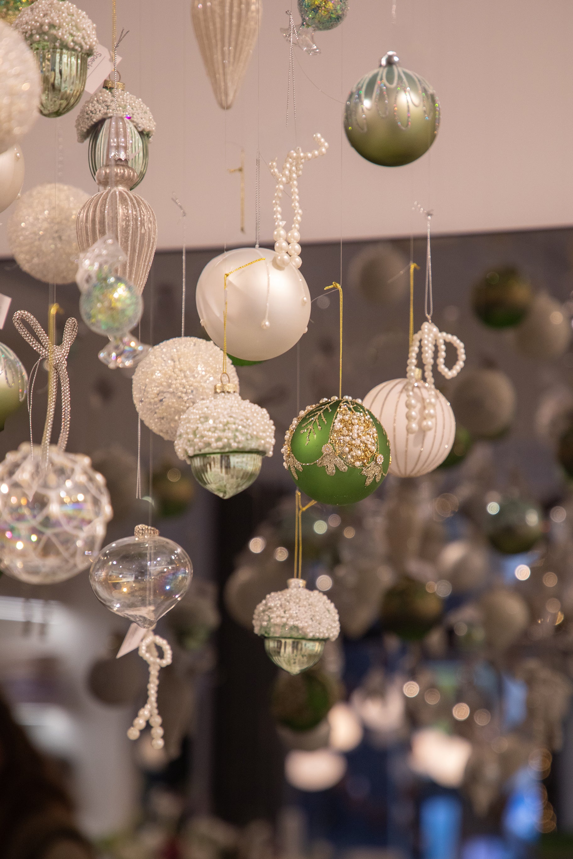 Grønne og hvide julekugler der hænger fra loftet.