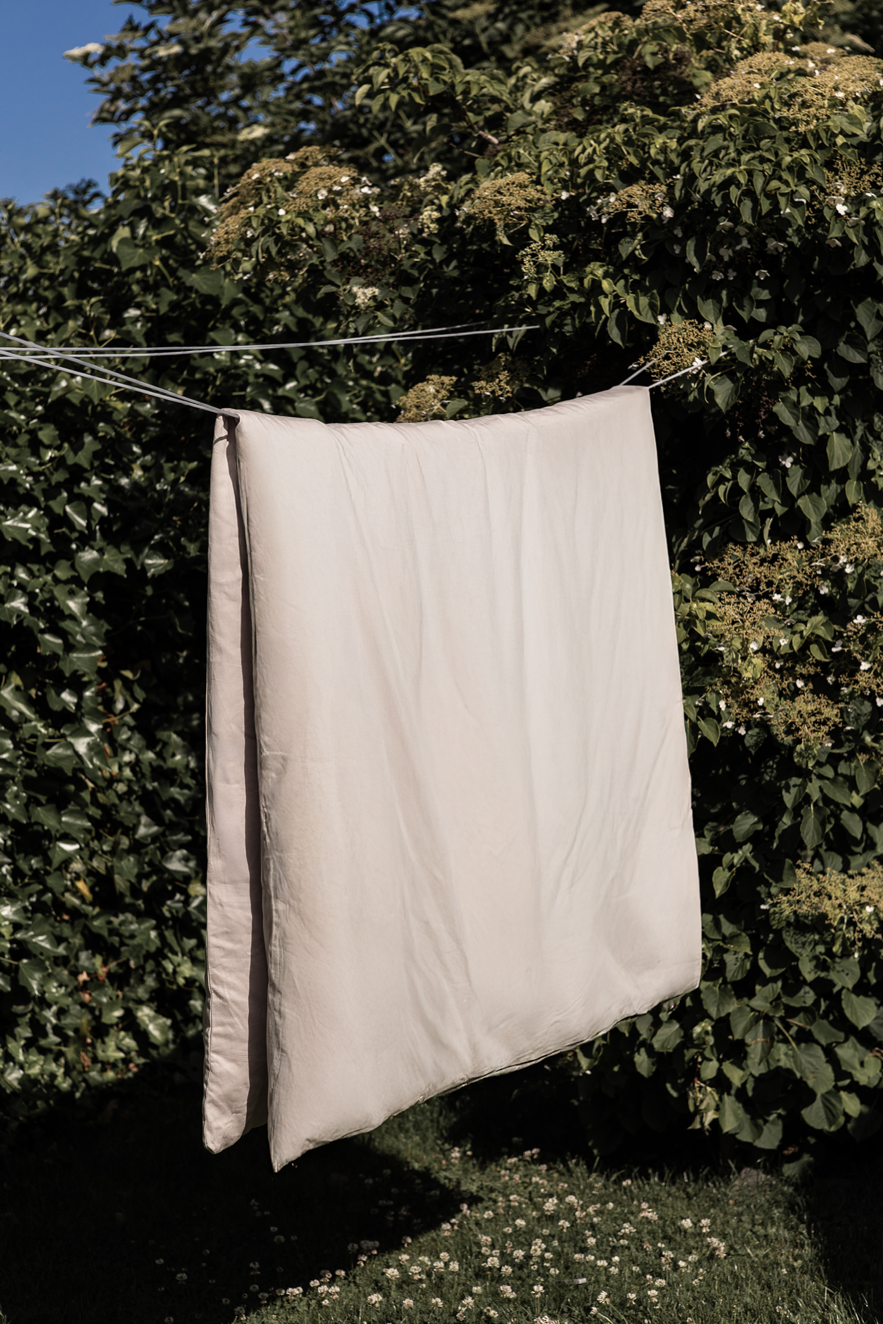 Økologisk sengetøj i bomuldssatin fra Specktrum, i en lys pudderfarve til ophæng i naturen.